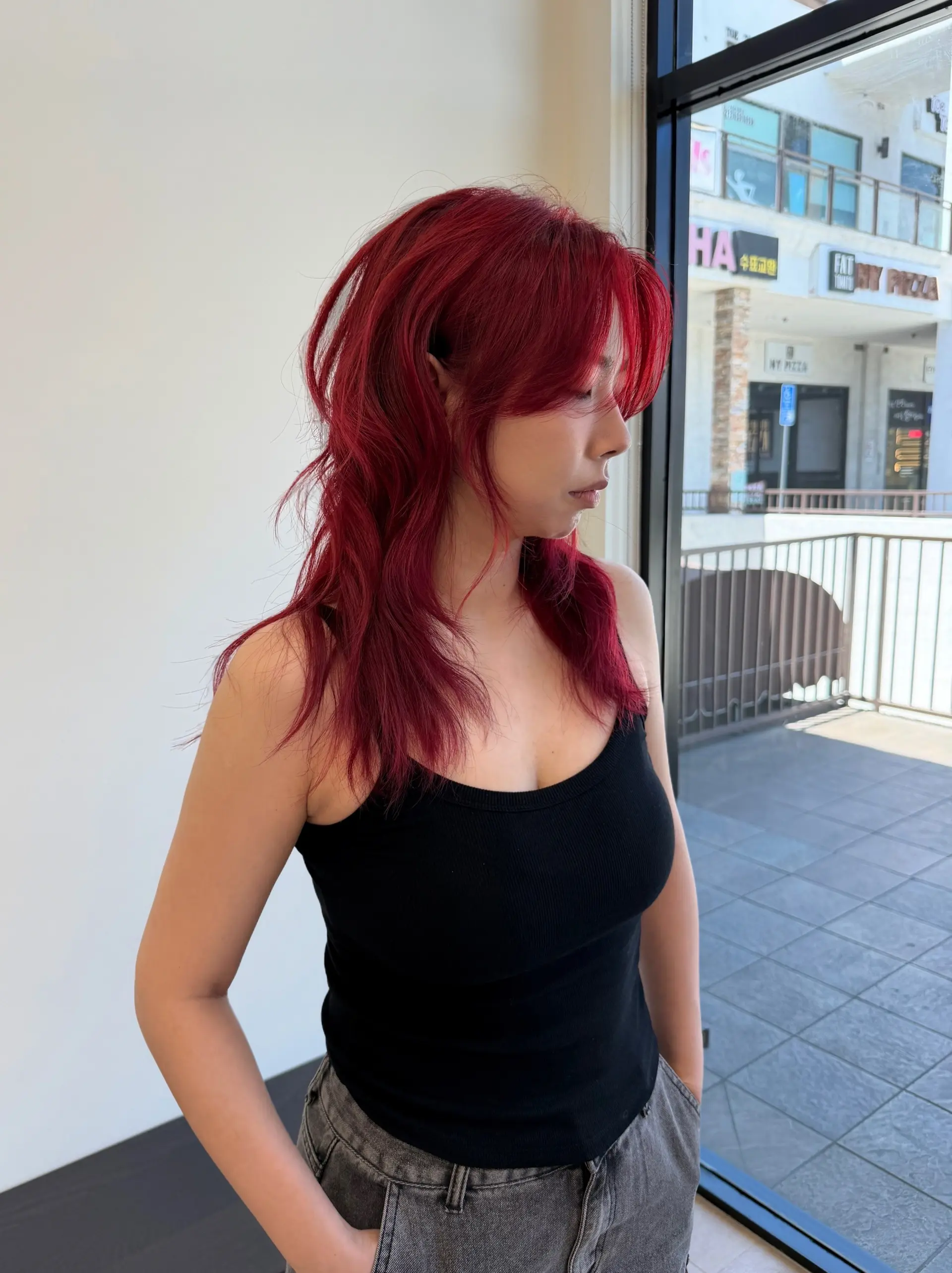 A textured, high-layered shag haircut styled with soft waves and curtain bangs in an all-over vibrant crimson red. 1