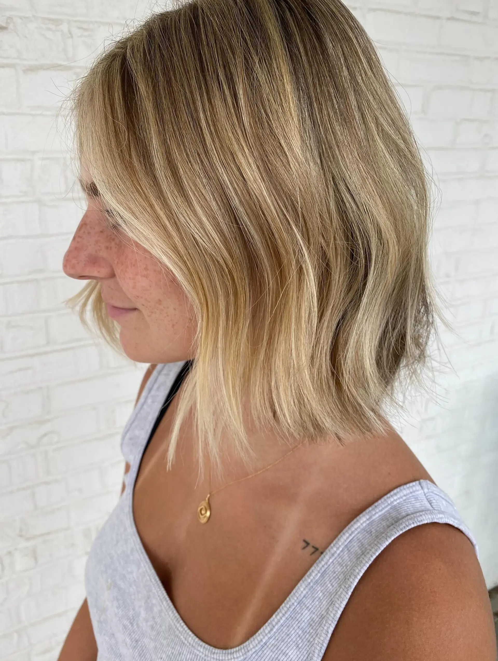 A textured, neck-length blunt bob featuring dimensional bright blonde highlights and subtle natural waves. 1