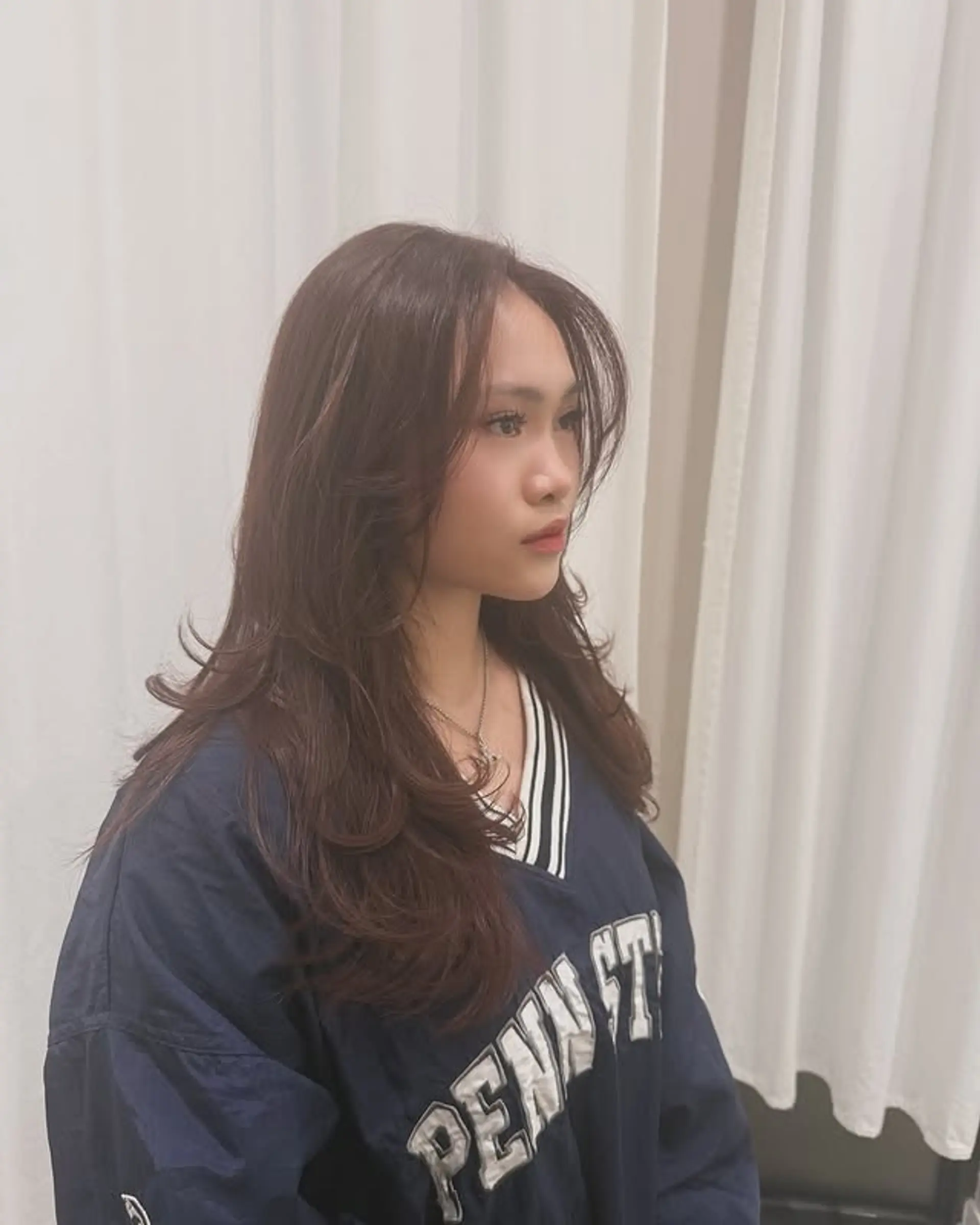 A long, layered hairstyle with soft waves and face-framing curtain bangs. 1