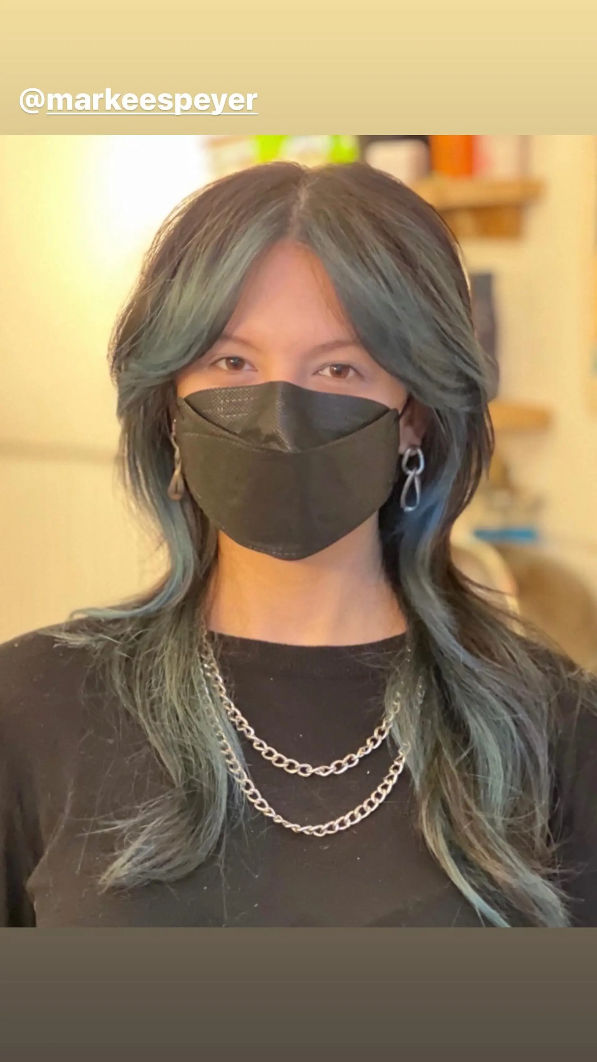 Long wavy hair with face-framing layers and curtain bangs, accented with teal highlights. 1