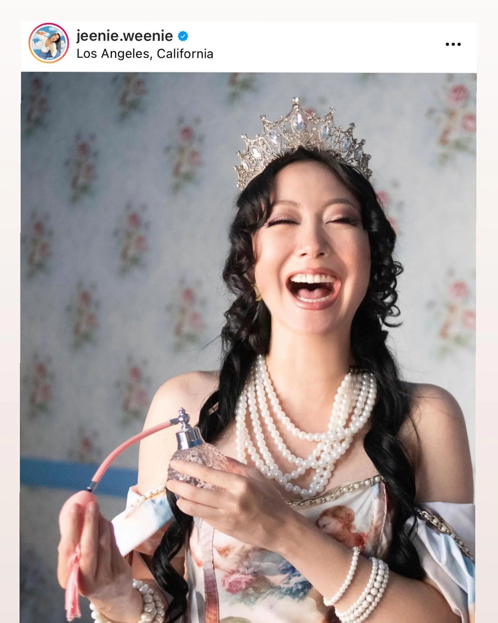 Long black hair styled into polished, bouncy ringlet curls adorned with a crown tiara. 1