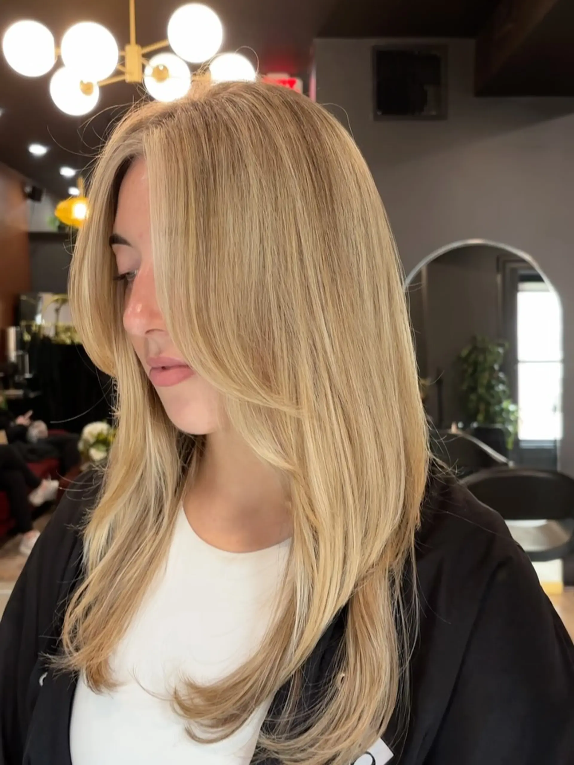 Long, sun-kissed golden blonde hair styled in a smooth blowout with soft face-framing layers and curved ends. 1