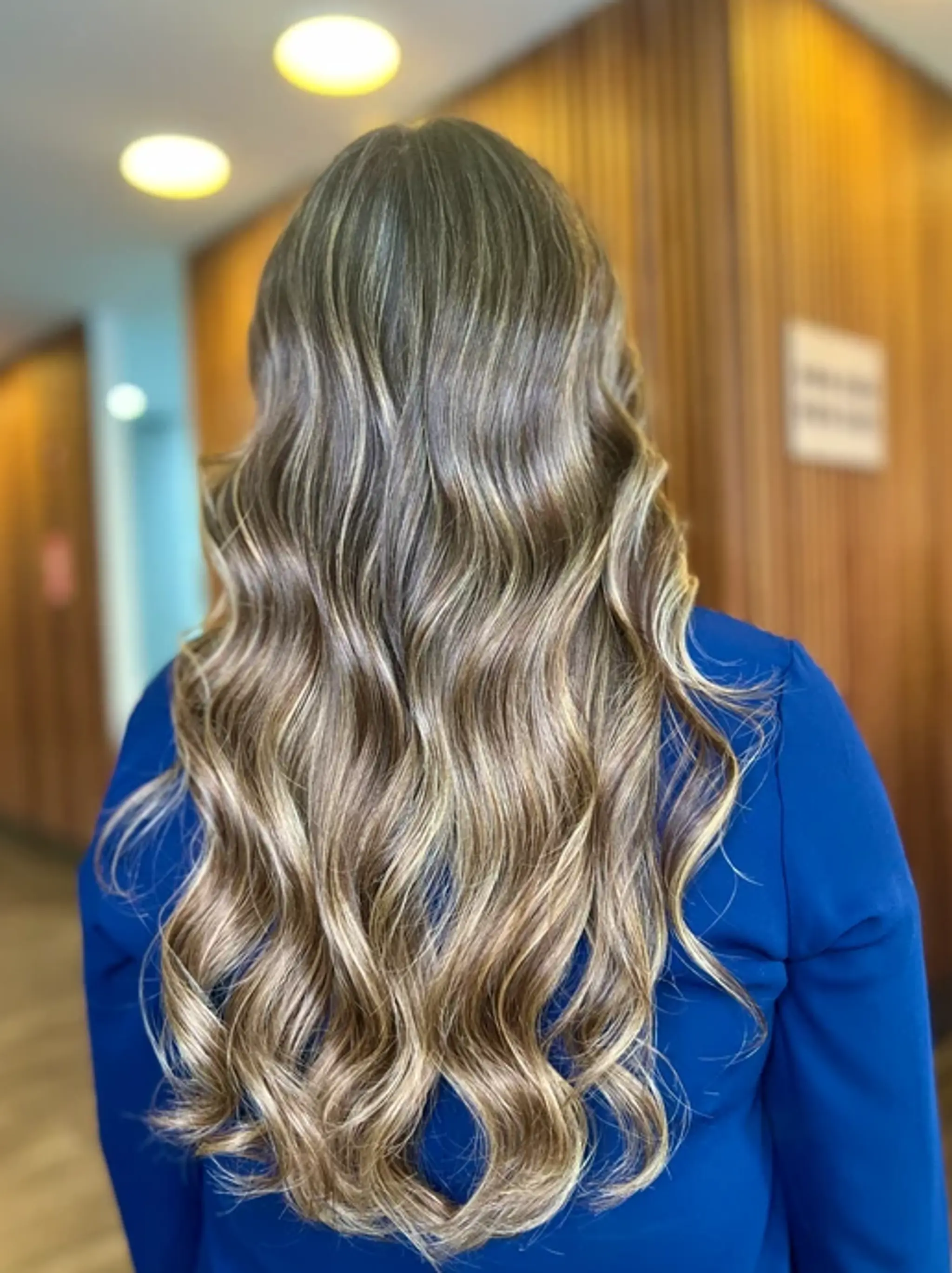 Long, wavy hair with soft, natural waves and subtle highlights in blonde, honey, and ash brown, creating an elegant, effortless look.