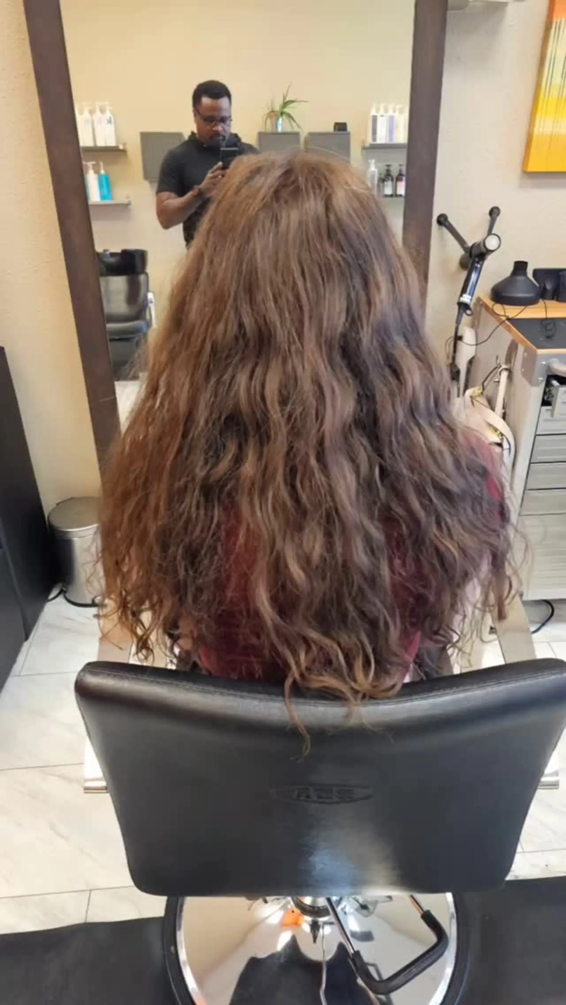 Long layered haircut enhancing natural wavy and curly texture on medium brown hair. 1