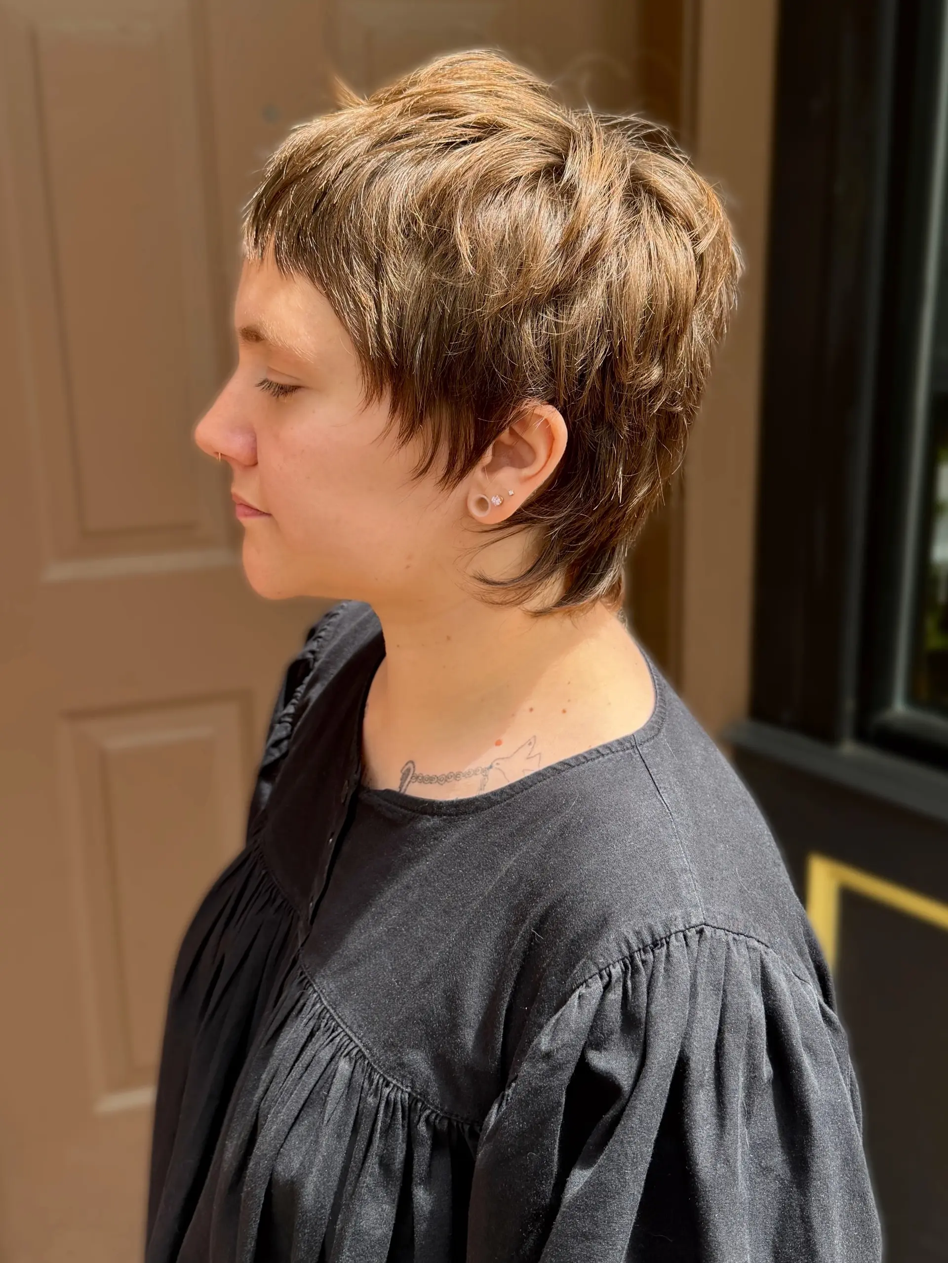 A textured shaggy pixie cut with micro bangs and tapered length around the ears and nape. 1