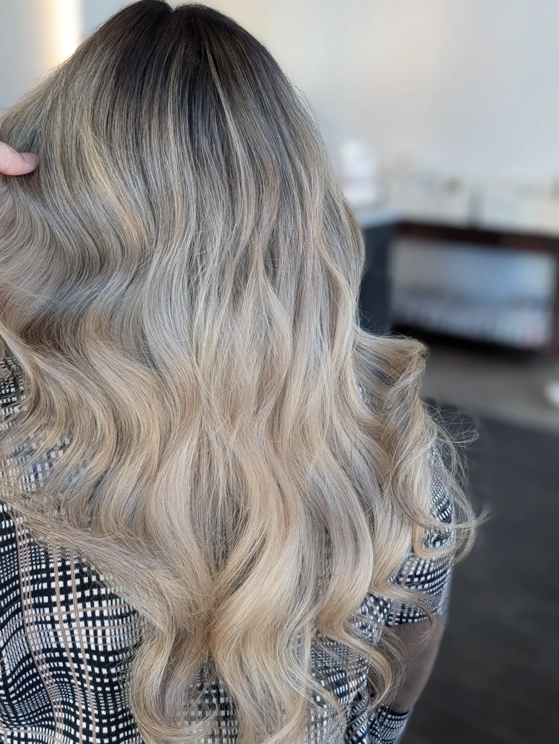 Long cascading hair styled in loose waves, featuring an ash blonde foilayage blended seamlessly into a dark shadow root. 1