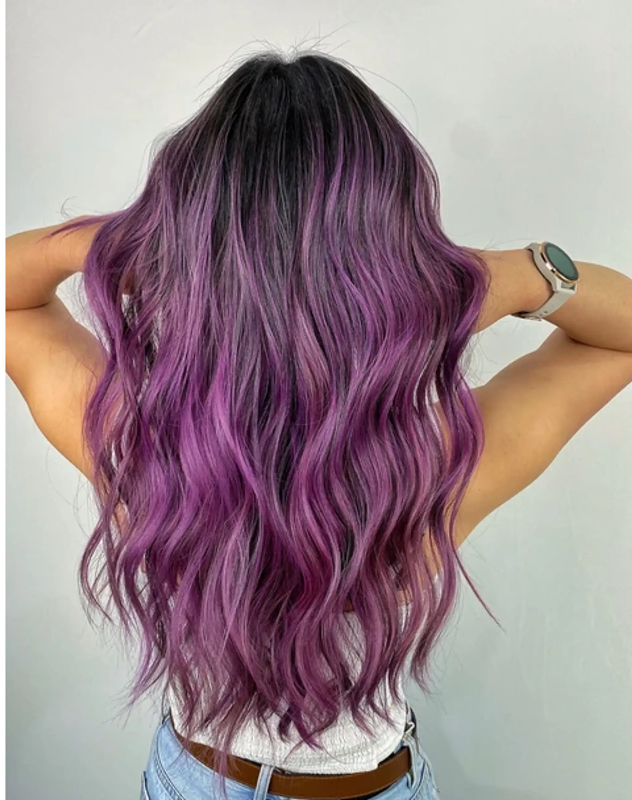 A long, wavy hairstyle with a black to purple gradient, featuring rich and varied purple tones and well-defined waves that add volume and movement.