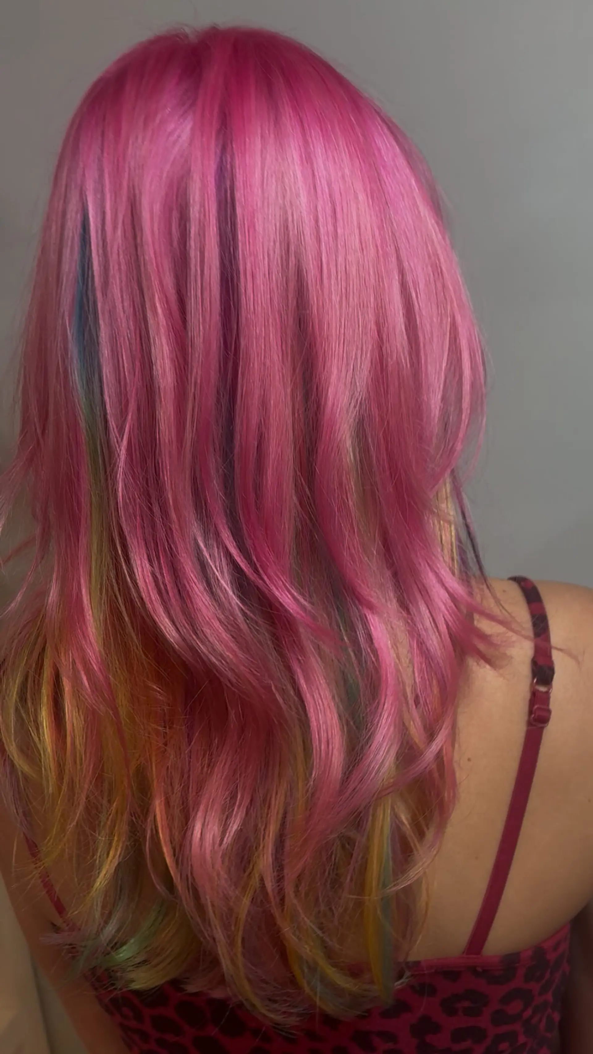 Bright hot pink layered hair accented with hidden rainbow peekaboo tones and subtle horizontal accent stripes beneath. 1