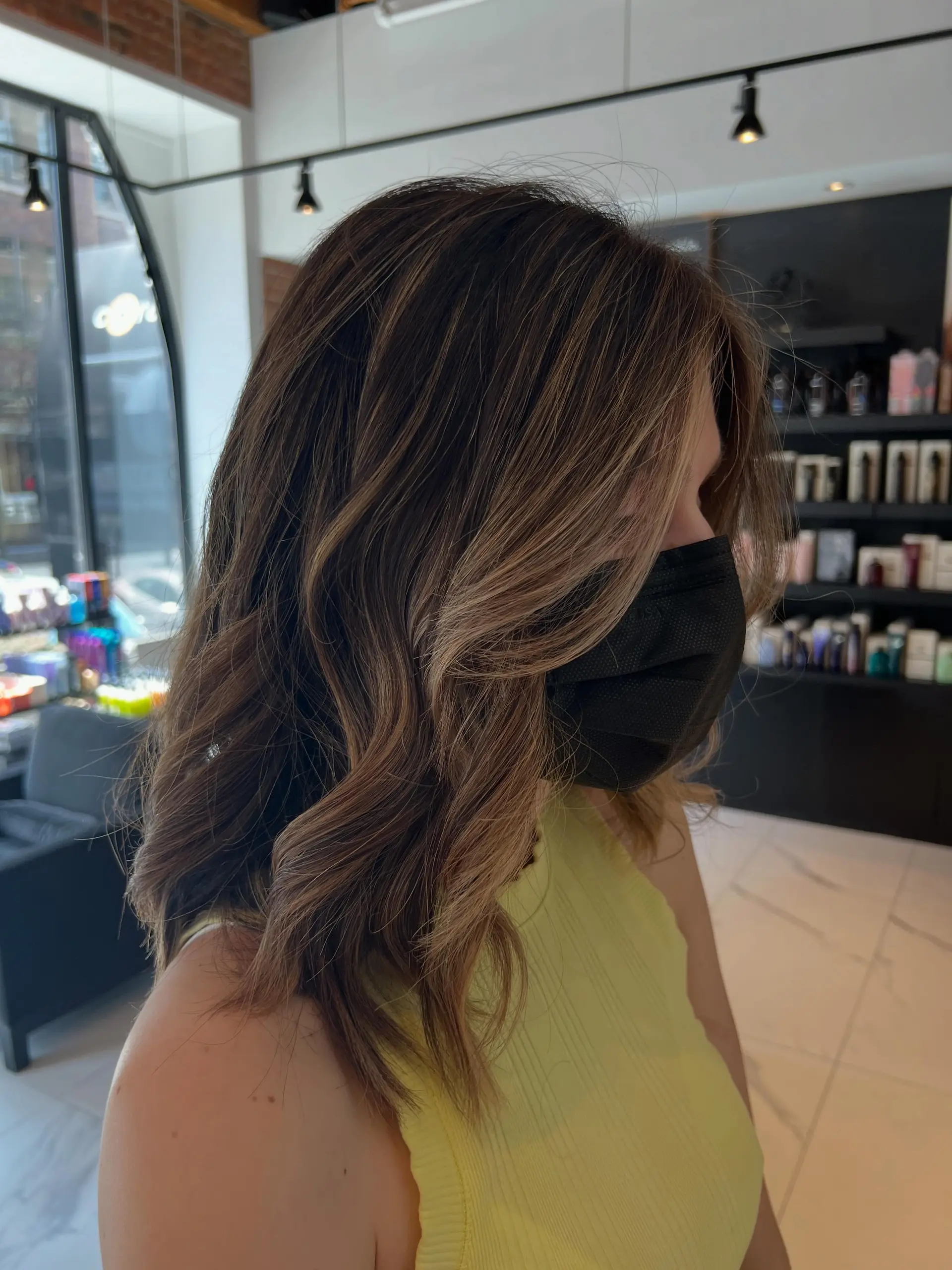 Medium-length brunette hair enhanced with seamless caramel balayage highlights and styled in soft, loose waves. 1