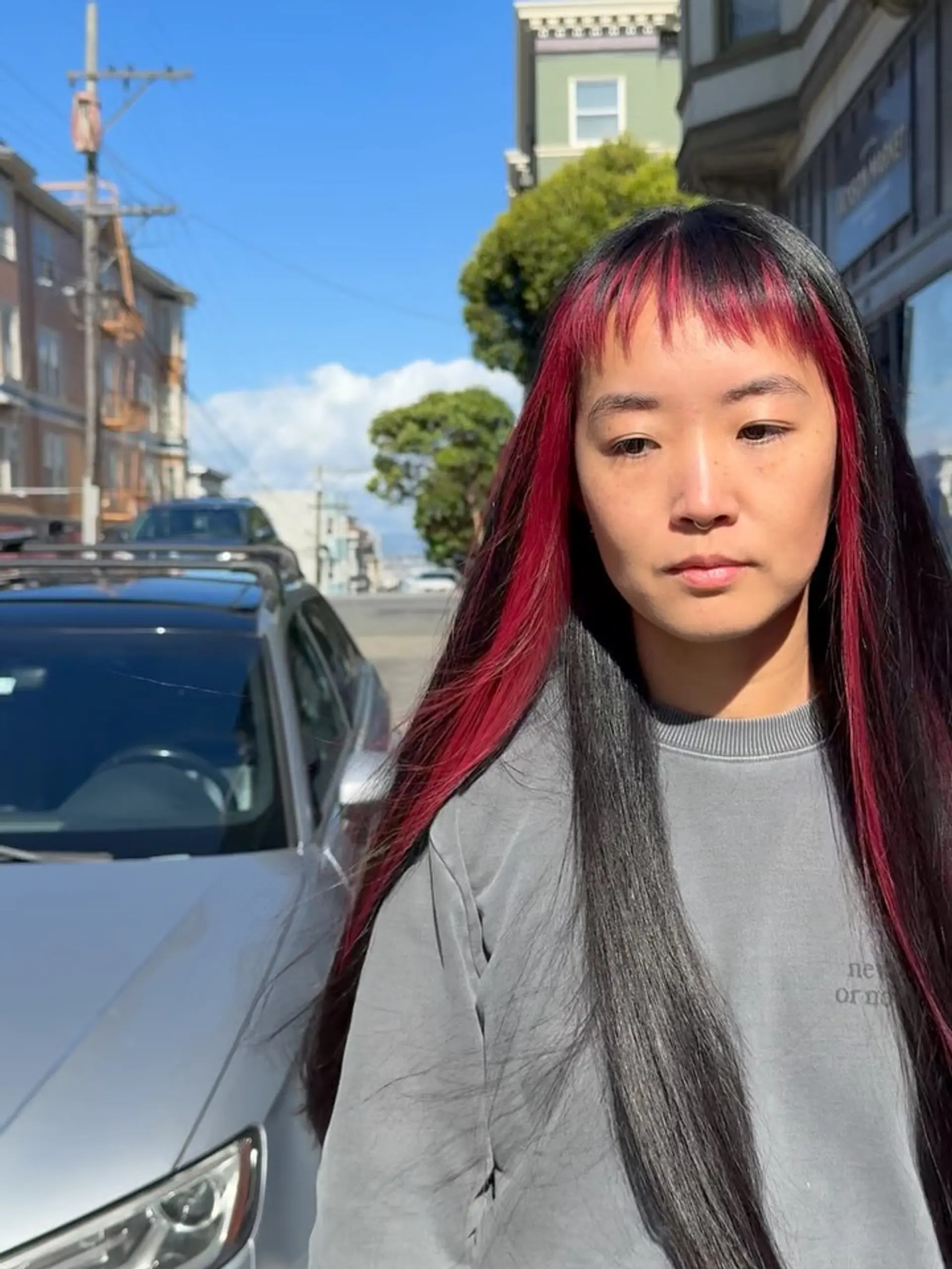 Extra-long straight dark hair featuring vivid magenta face-framing sections and choppy micro bangs. 1
