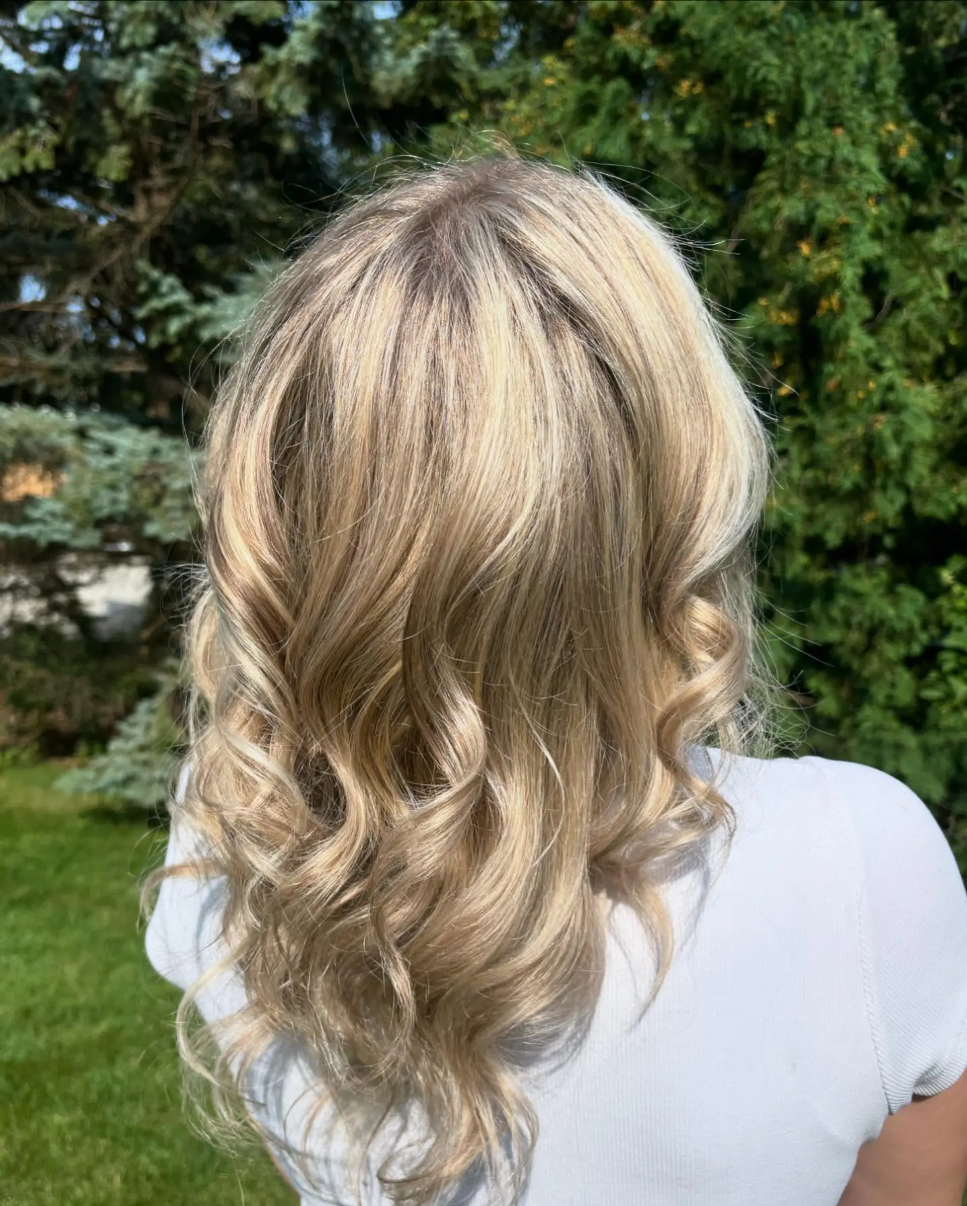 Medium-length dimensional blonde hair with full highlights styled into loose, bouncy curls. 1