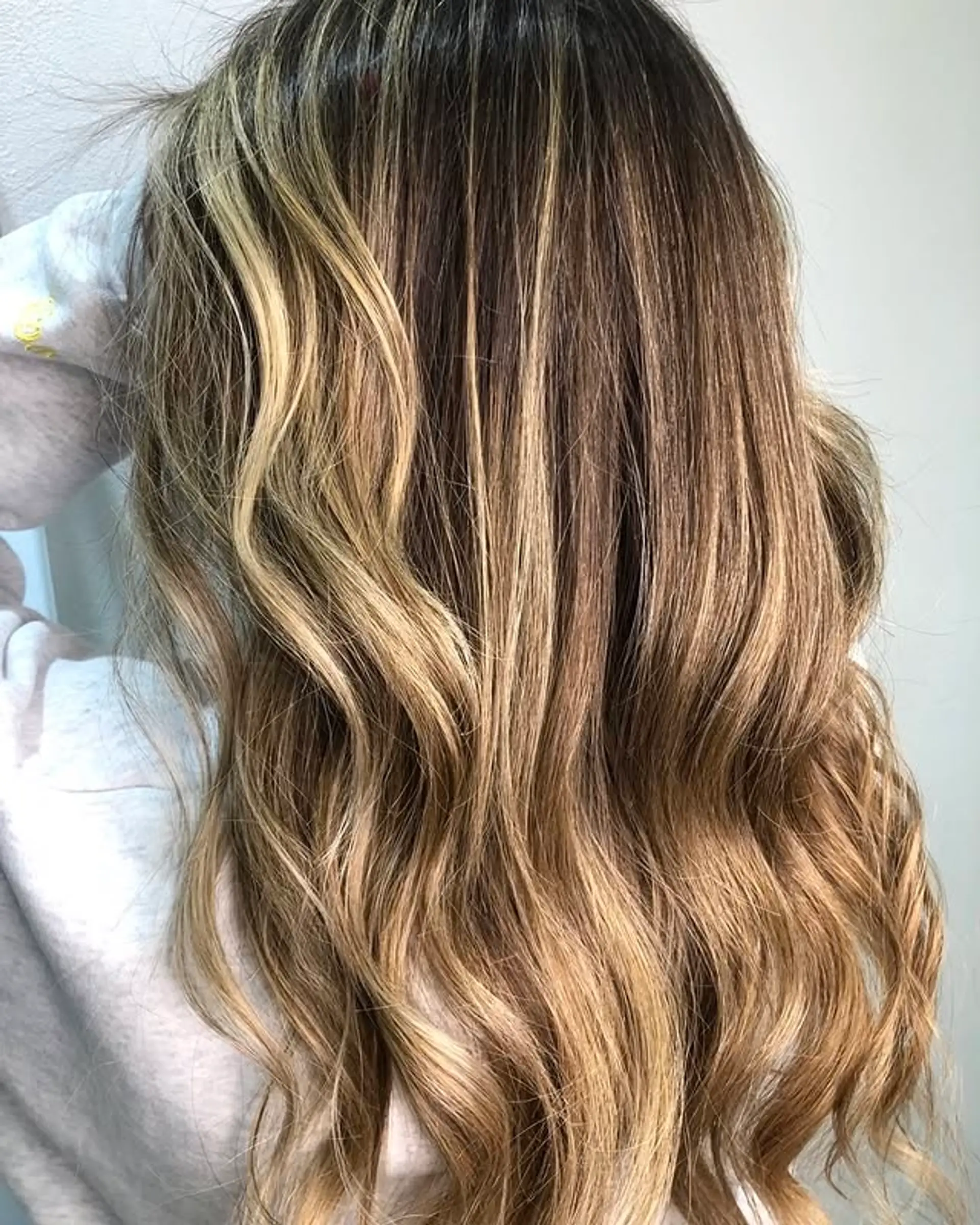 Wavy long hair with a balayage bronde color and rooted highlights. 1