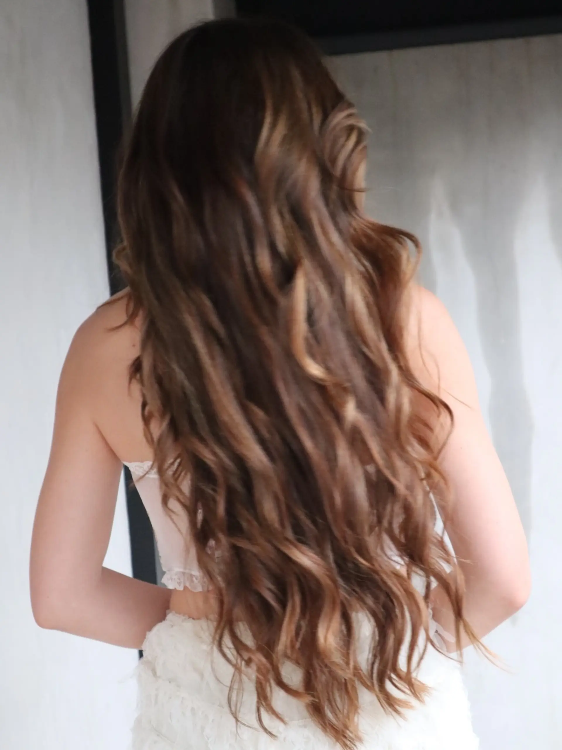 Extra long, loose wavy hair in a warm chestnut brown hue with subtle caramel dimensional highlights. 1