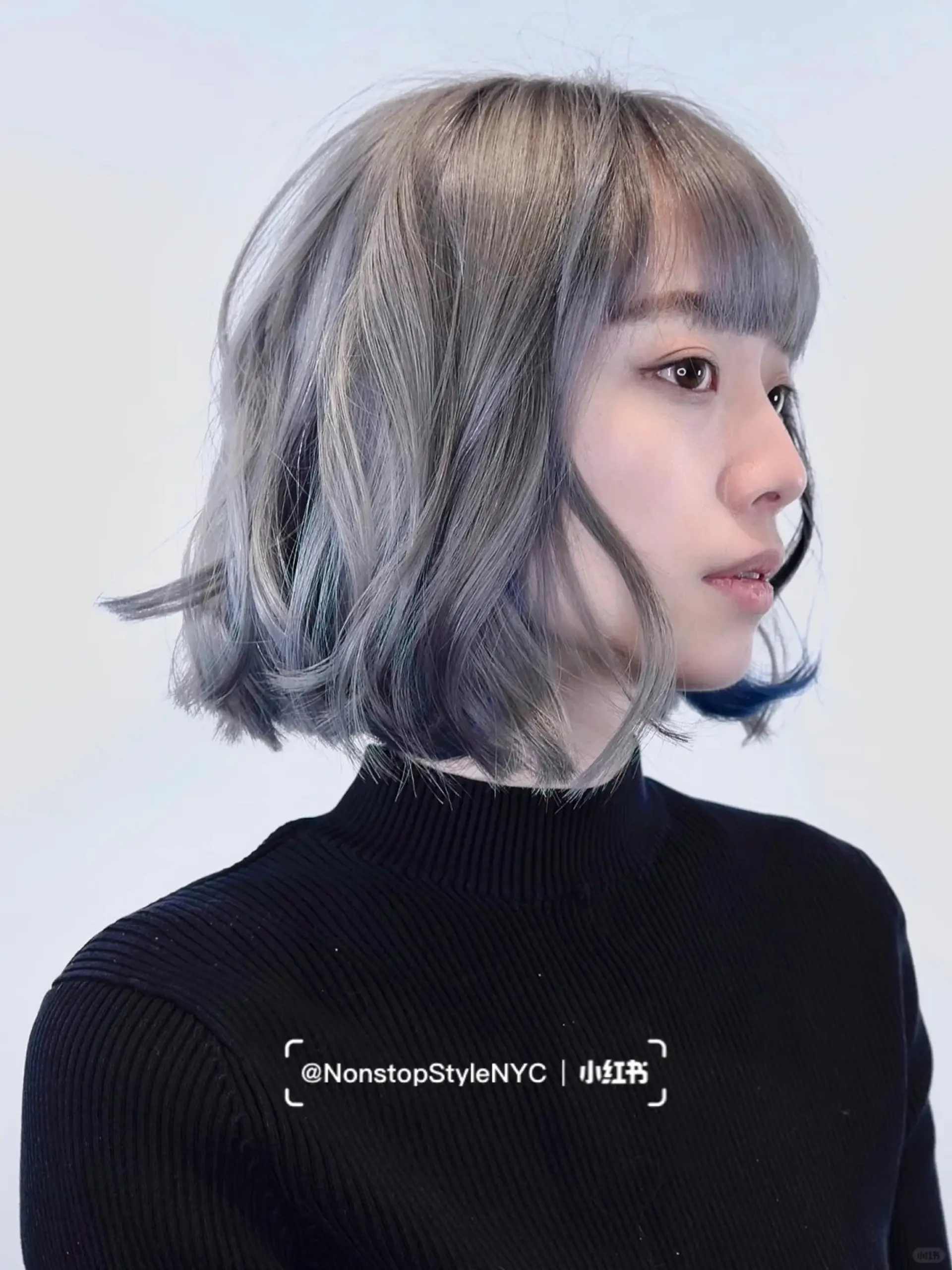 A modern bob haircut with loose, natural waves and straight-across bangs. The hair is shoulder-length, wavy, and colored in shades of silver and gray. Slightly layered ends add movement and volume.

 1