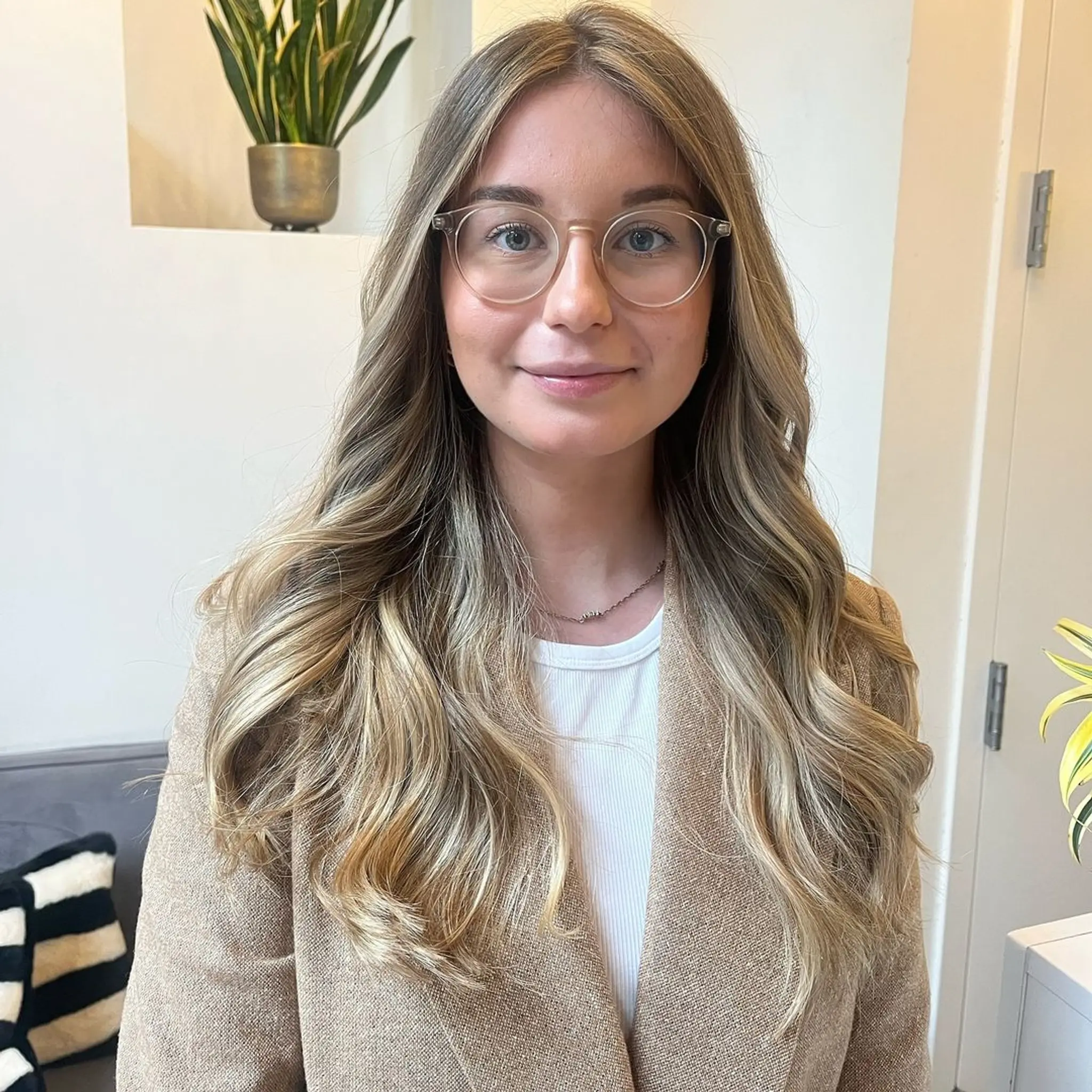 Long, wavy hair with a middle part, layered cut, and face-framing layers in a mix of blonde and light brown with golden highlights.