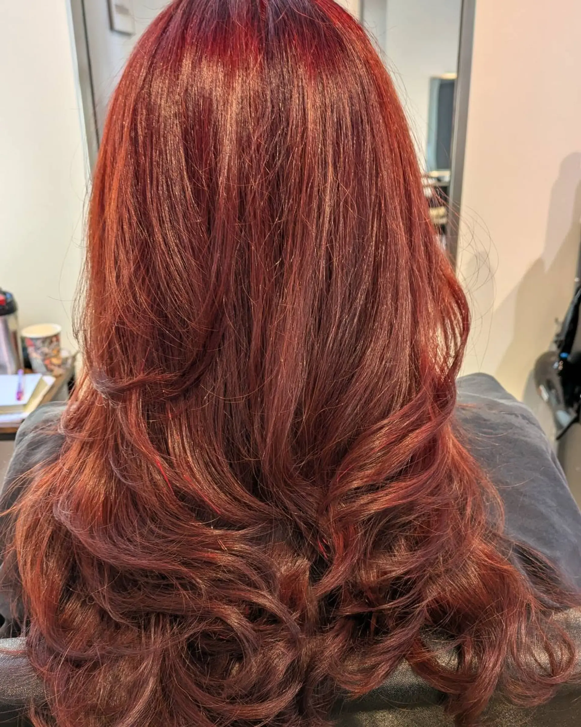 Long vibrant red velvet hair cut into soft flowing layers with flipped and curled ends. 1