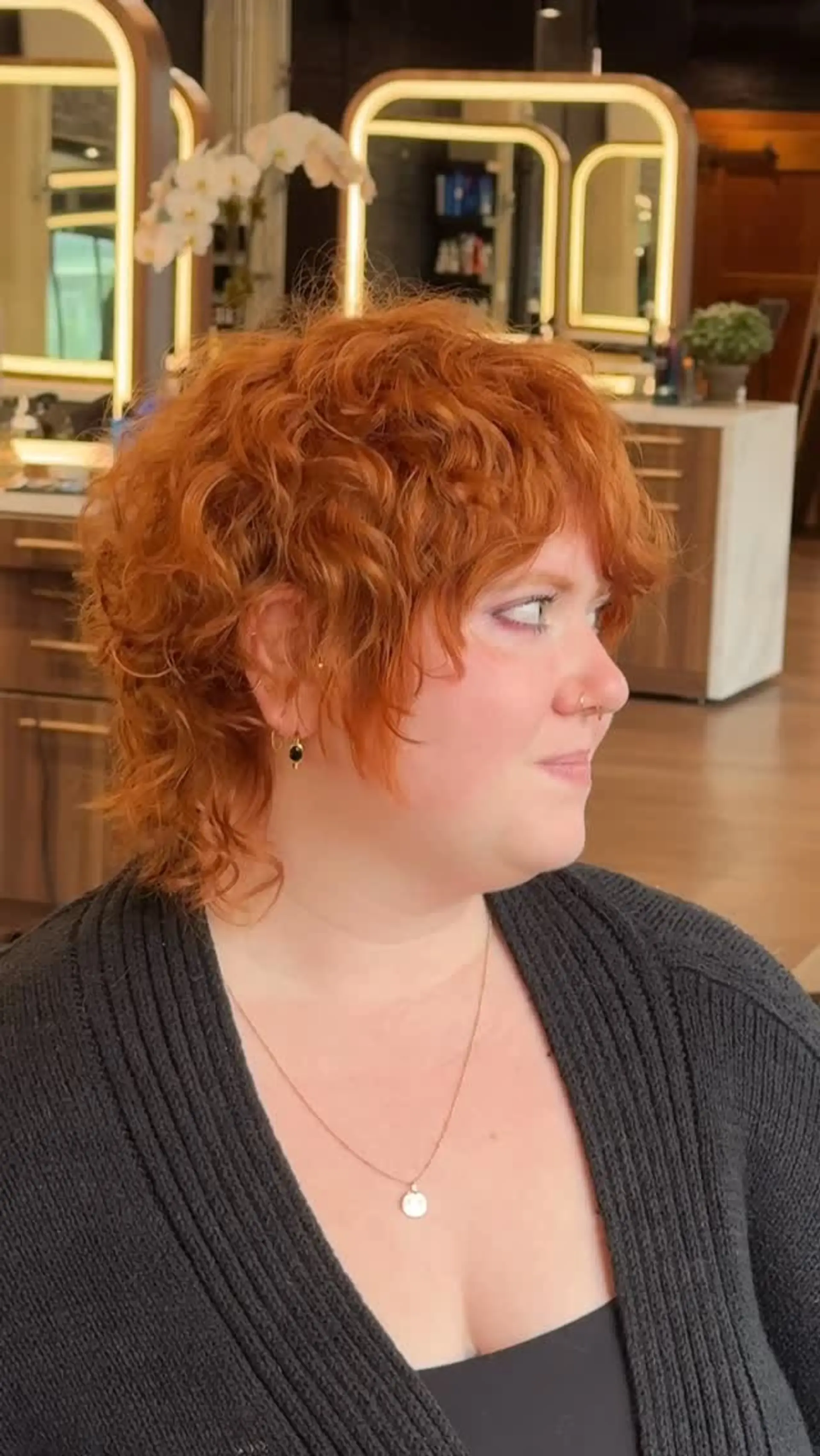 A textured curly shag haircut in a rich copper tone featuring layered volume and wispy curly bangs. 1