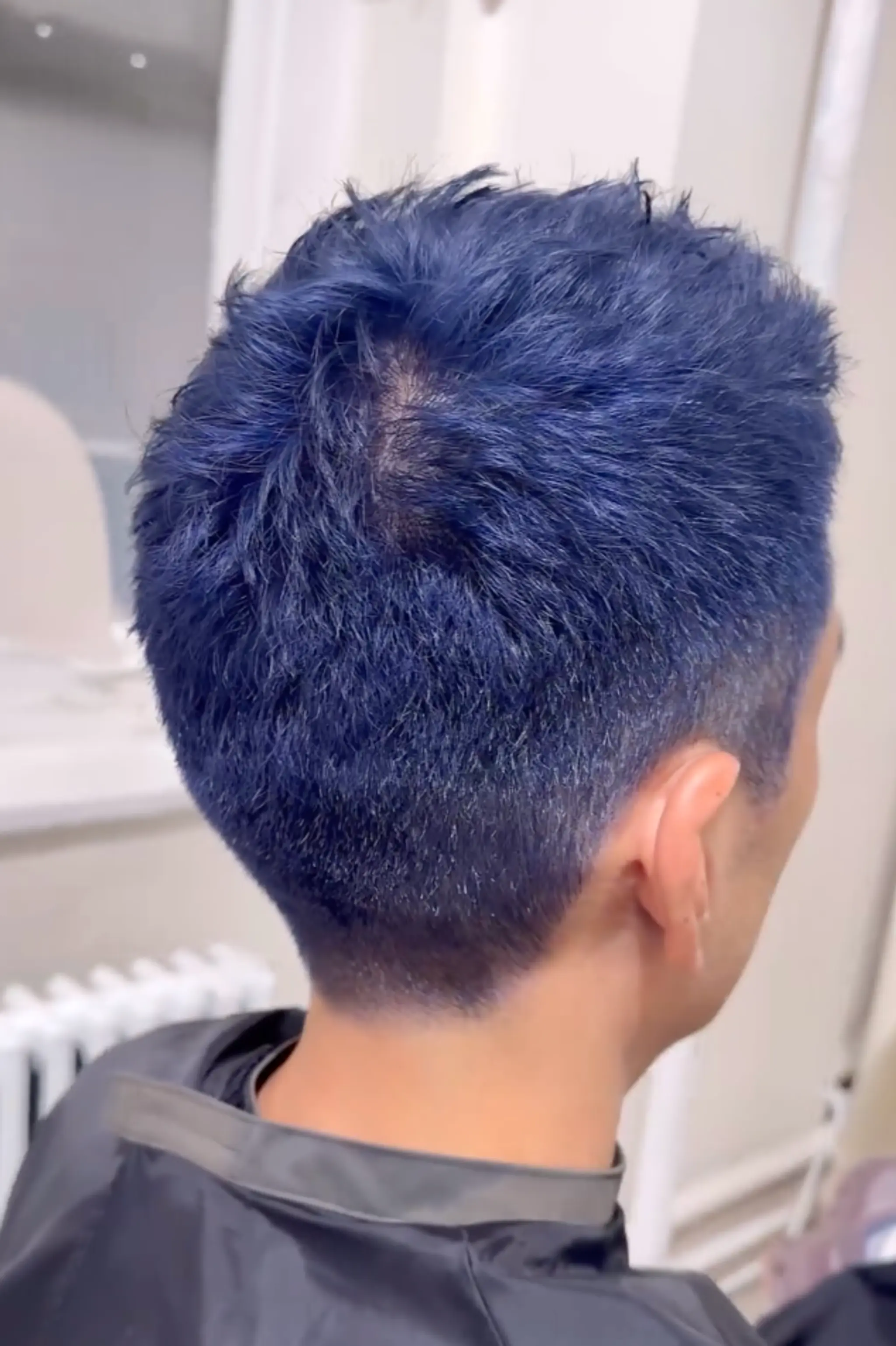 Short, vivid blue buzz cut with tapered sides, straight texture.

