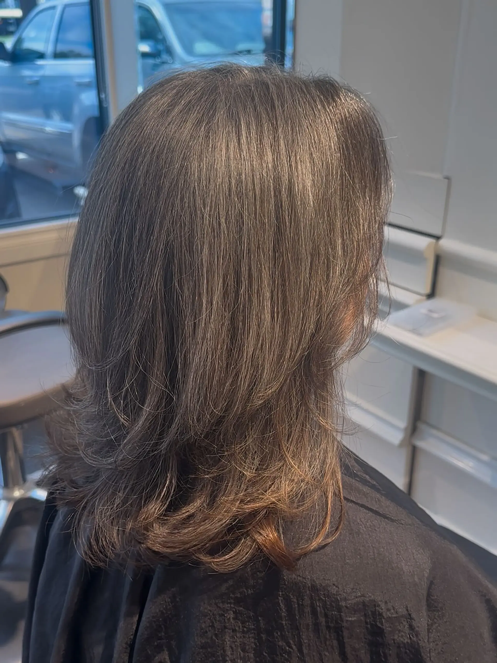 Medium-length brunette hair styled with soft, textured layers and outward-curling ends. 1