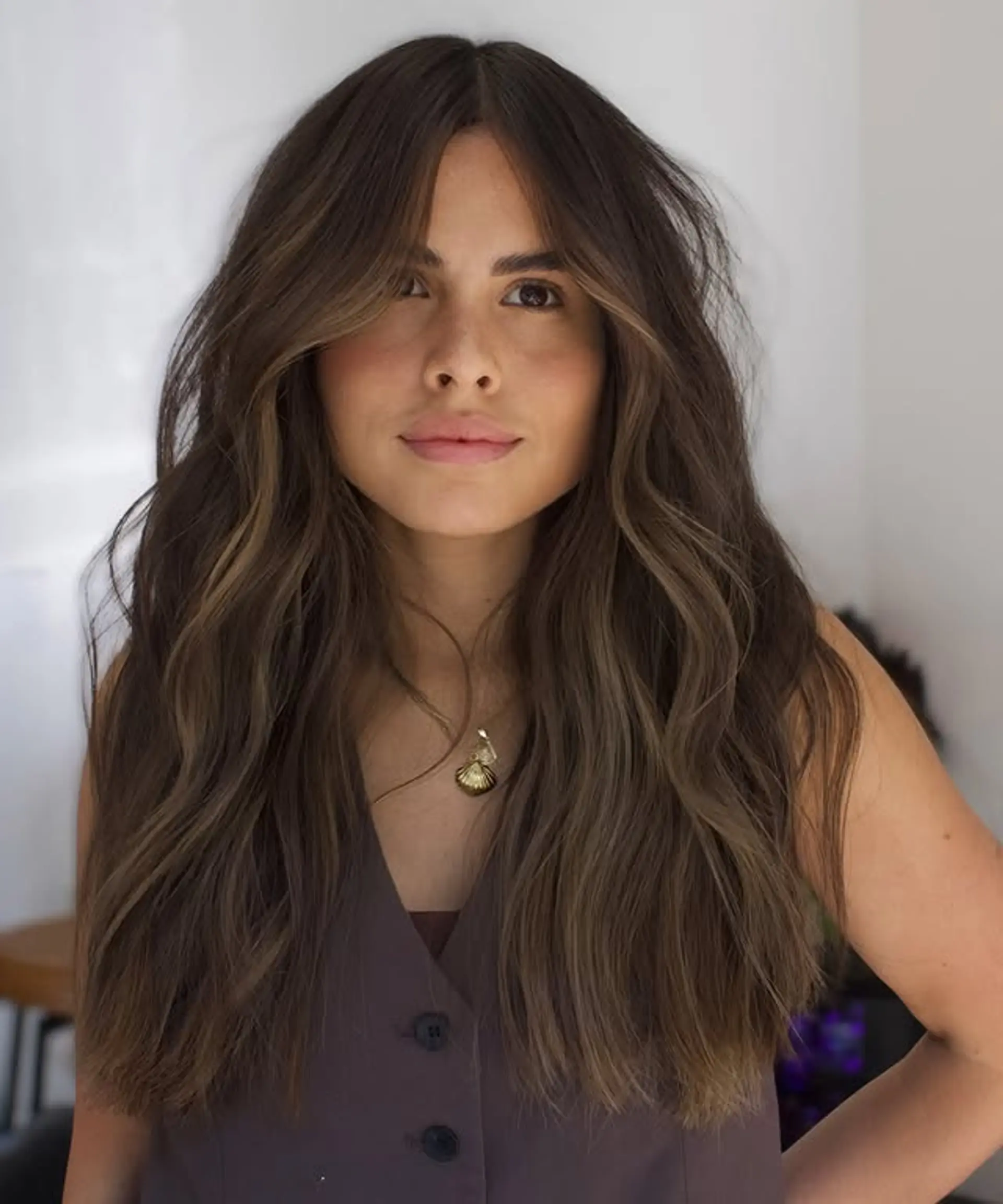 Long, wavy hair with face-framing layers and a balayage effect, creating a bronzed, dimensional look. 1