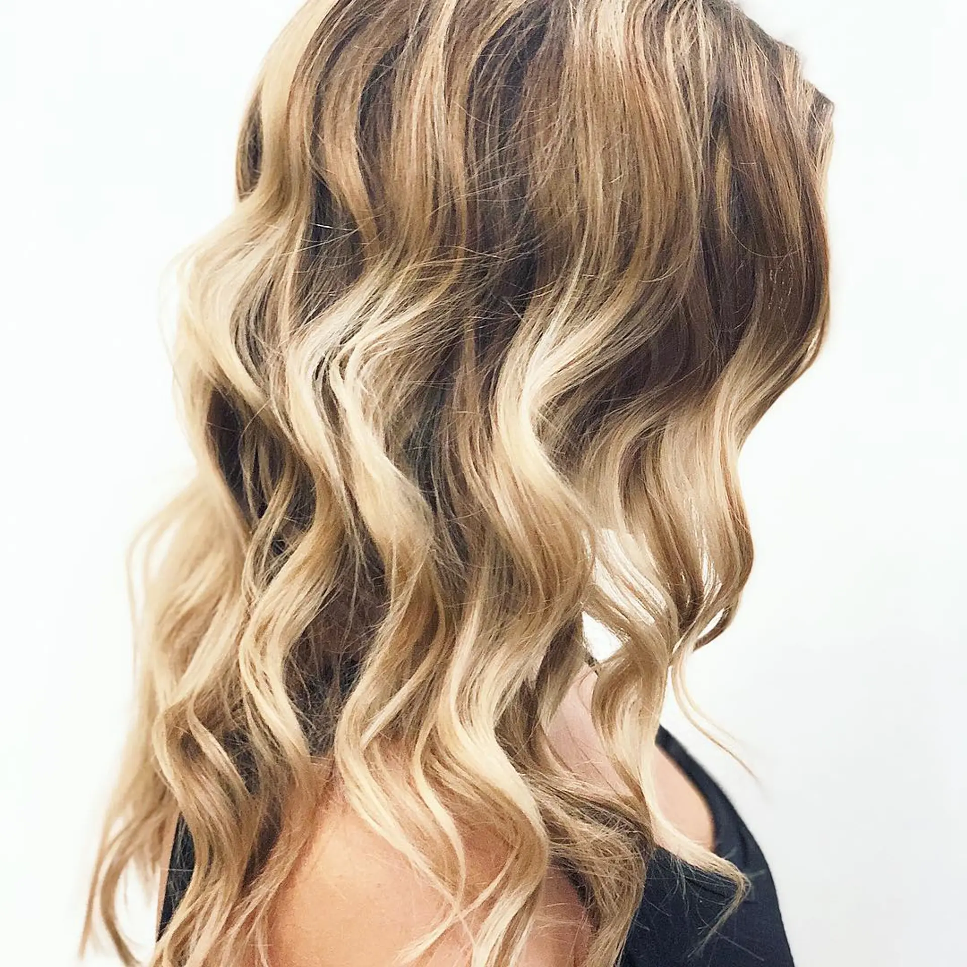 Long hair featuring a seamless balayage color melt from light brown roots to bright blonde ribbons, styled in textured, loose waves. 1