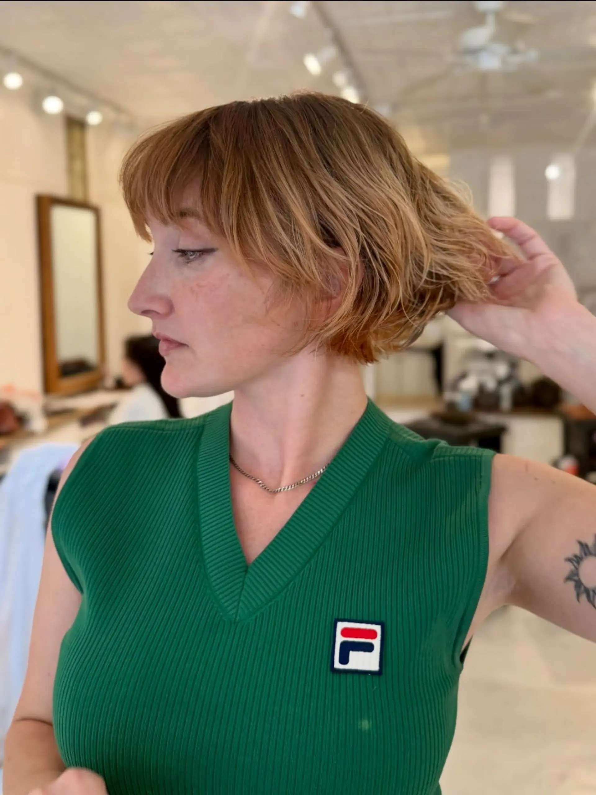 A textured short bob haircut featuring piecey, feathered bangs and dimensional warm honey blonde highlights. 1