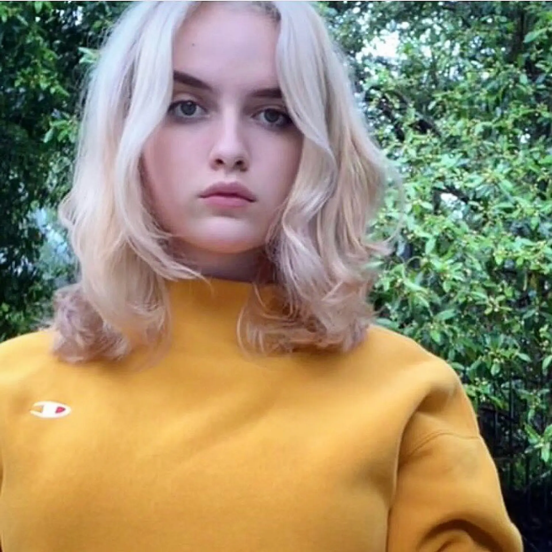 Shoulder-length platinum blonde hair styled with soft, face-framing waves and parted down the center. 1