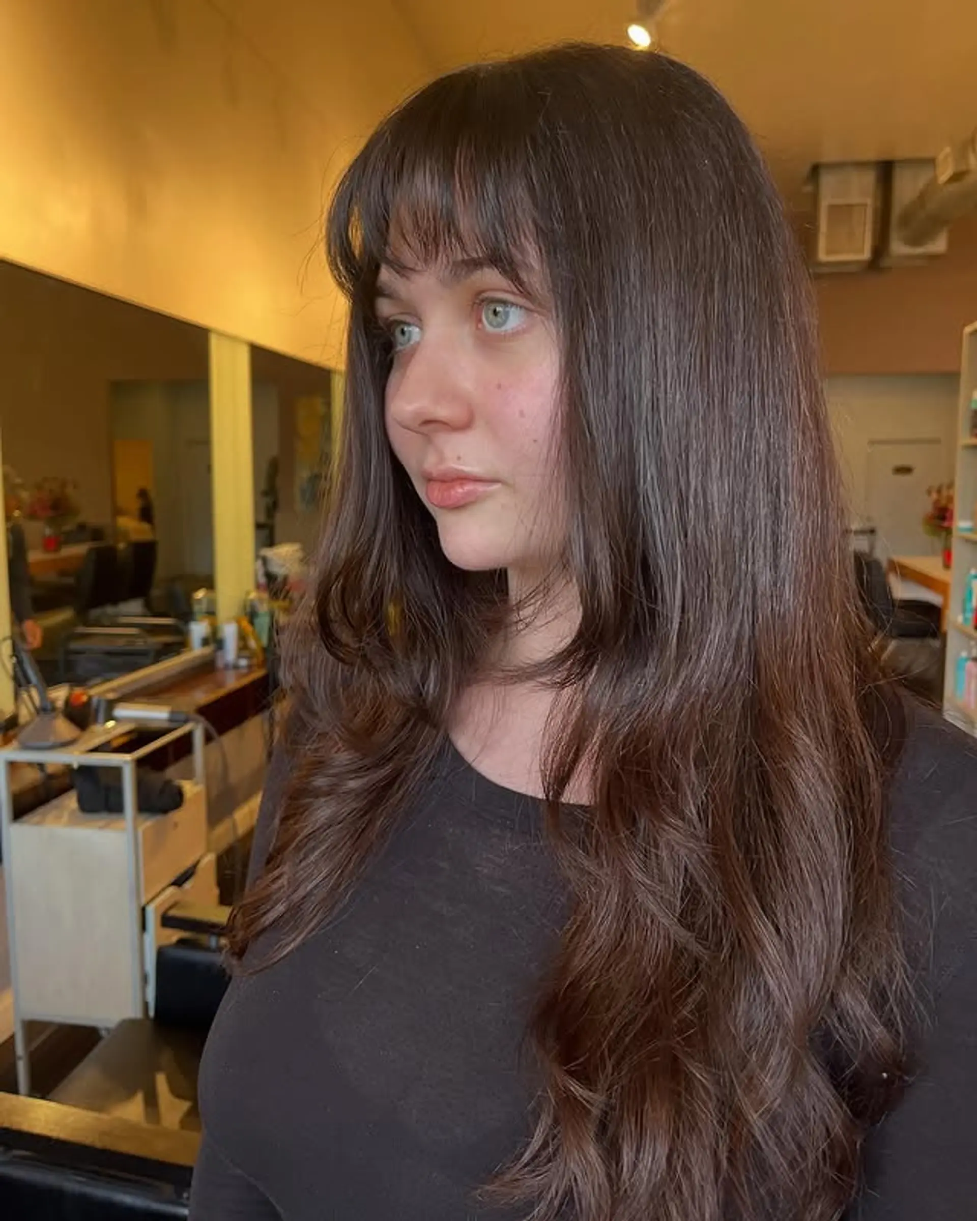 A long layered haircut with curtain bangs and soft waves. 1