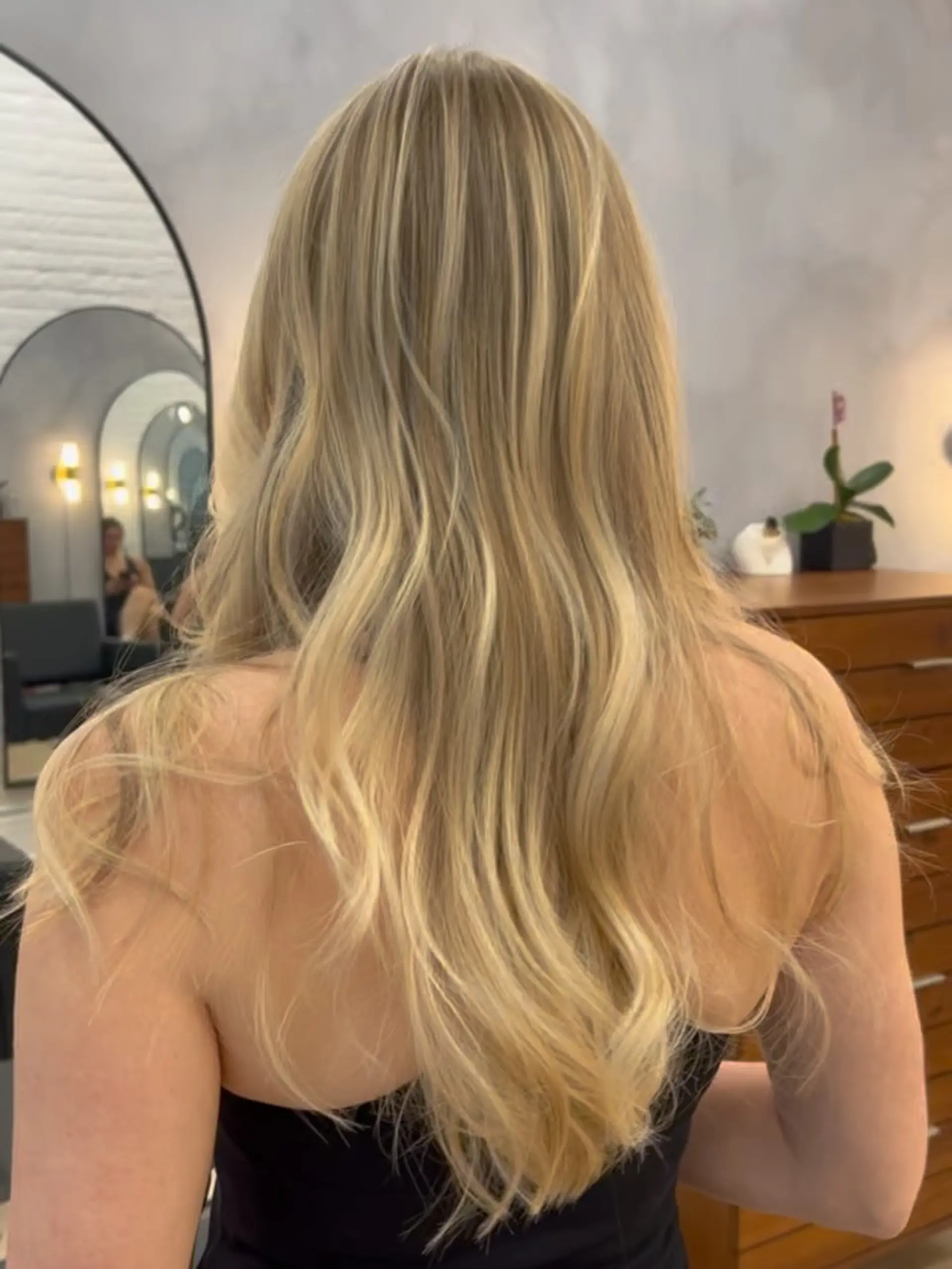 Long dimensional blonde hair styled into smooth, loose waves. 1