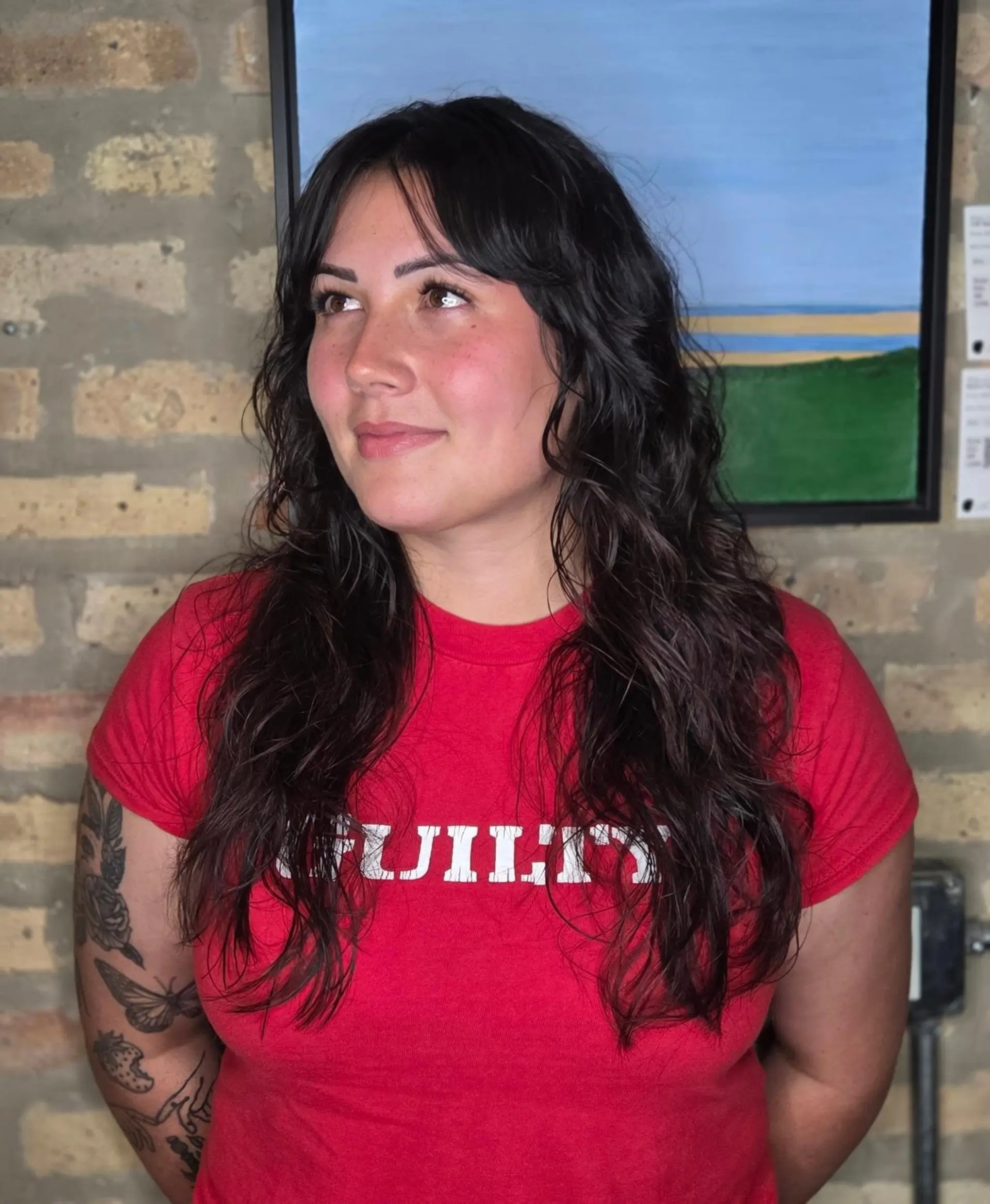 A long textured shag haircut featuring wispy curtain bangs and soft, natural waves. 1