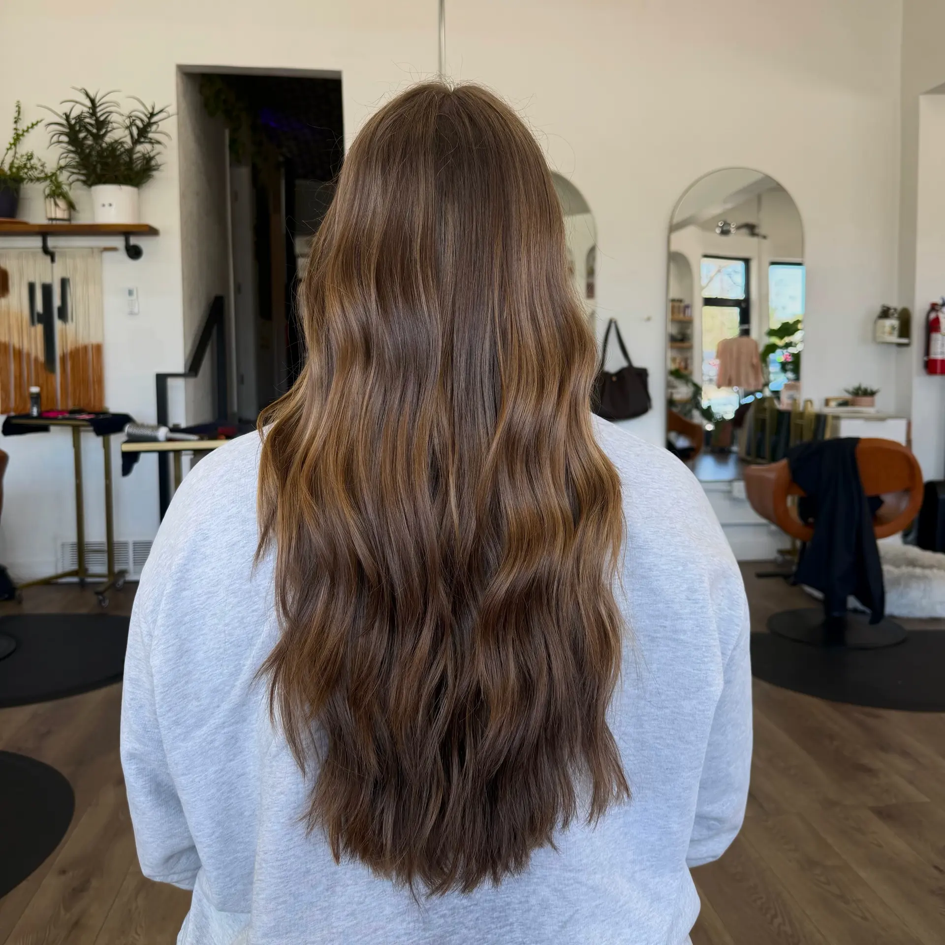 Long dimensional warm brunette hair styled into soft, natural lived-in waves. 1