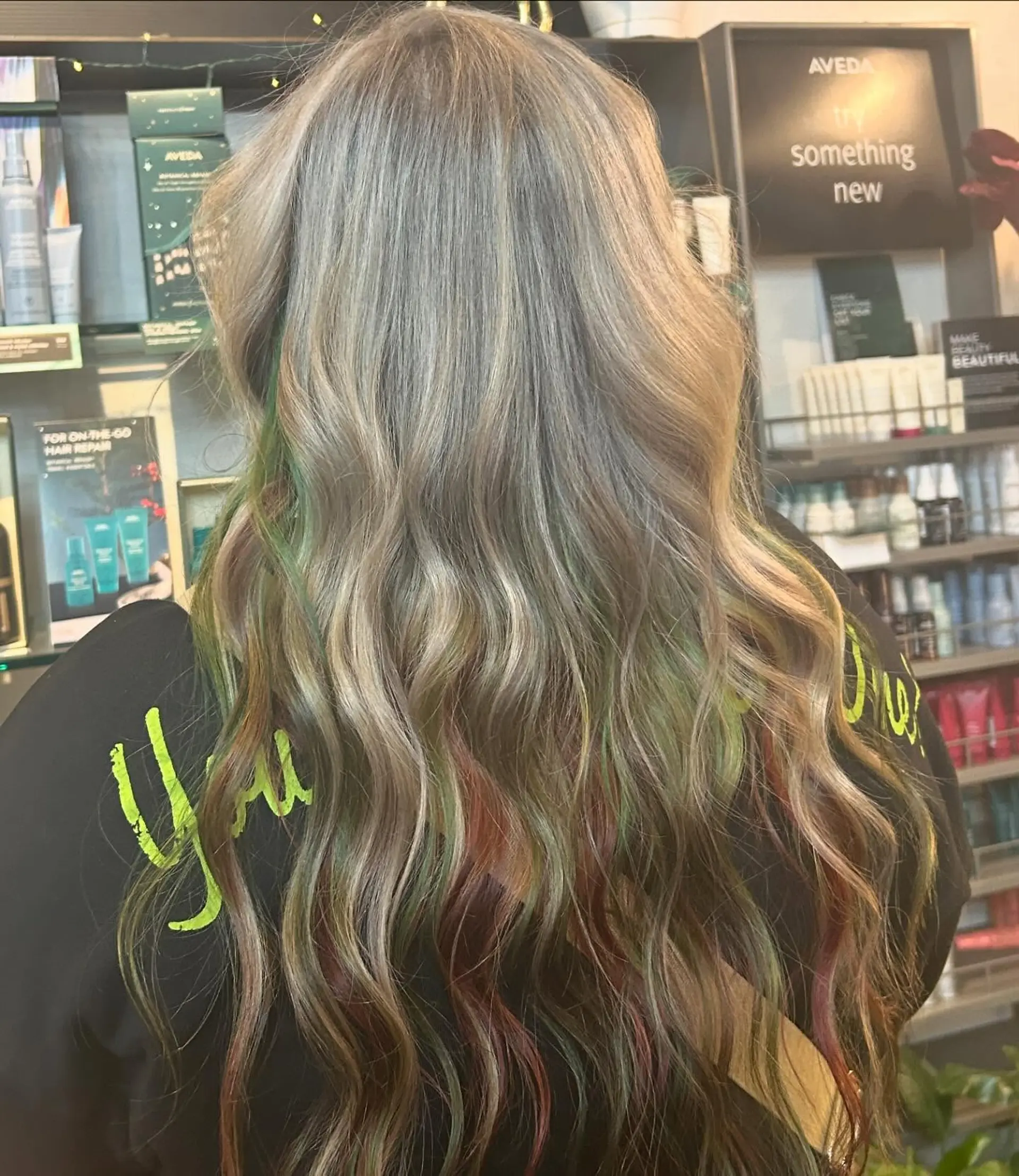 Long, tousled ash blonde waves revealing hidden peekaboo strands of vibrant green and red underneath. 1