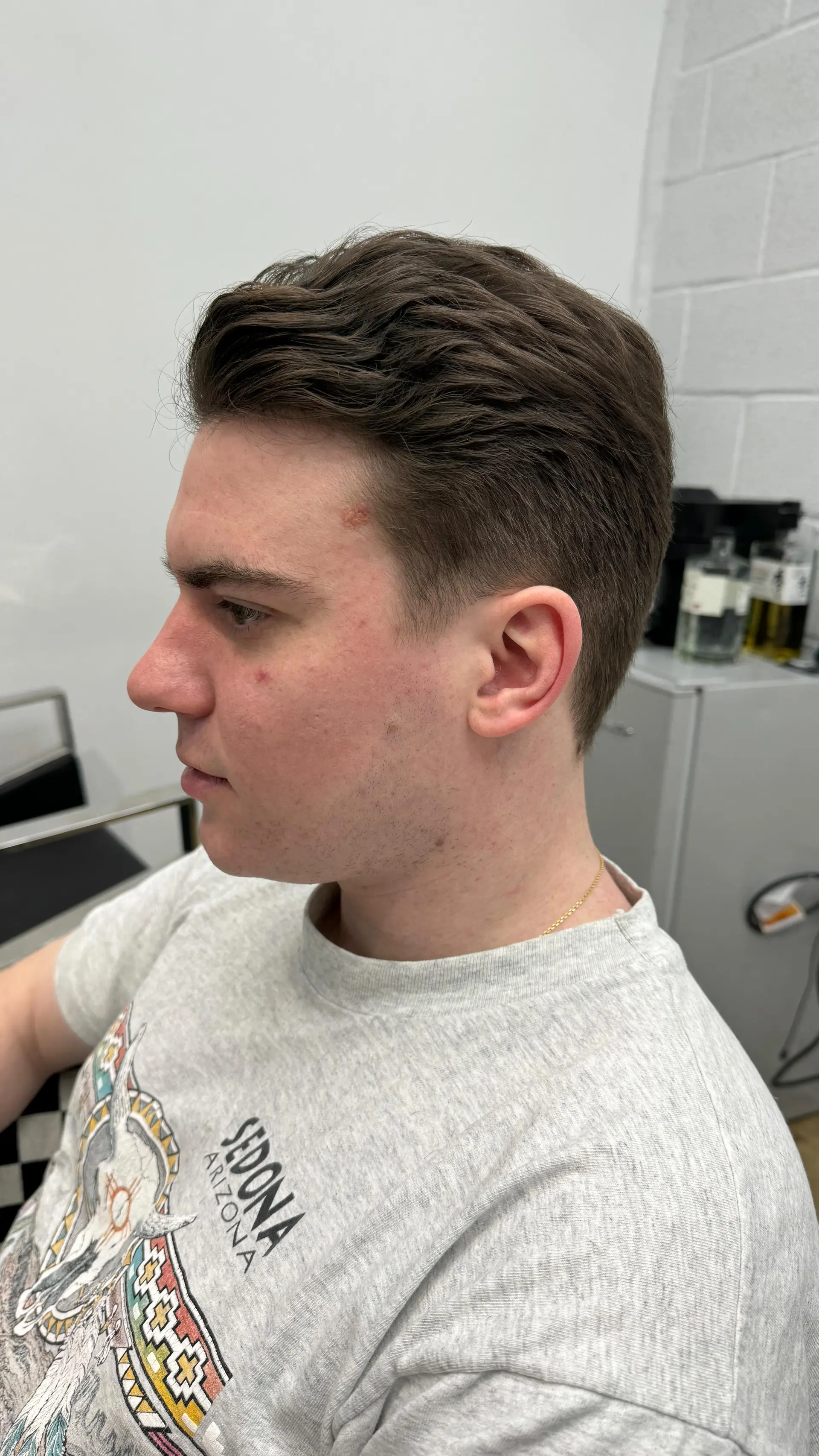 A clean, modern men's taper haircut featuring natural wavy texture swept back on top and neatly blended sides. 1