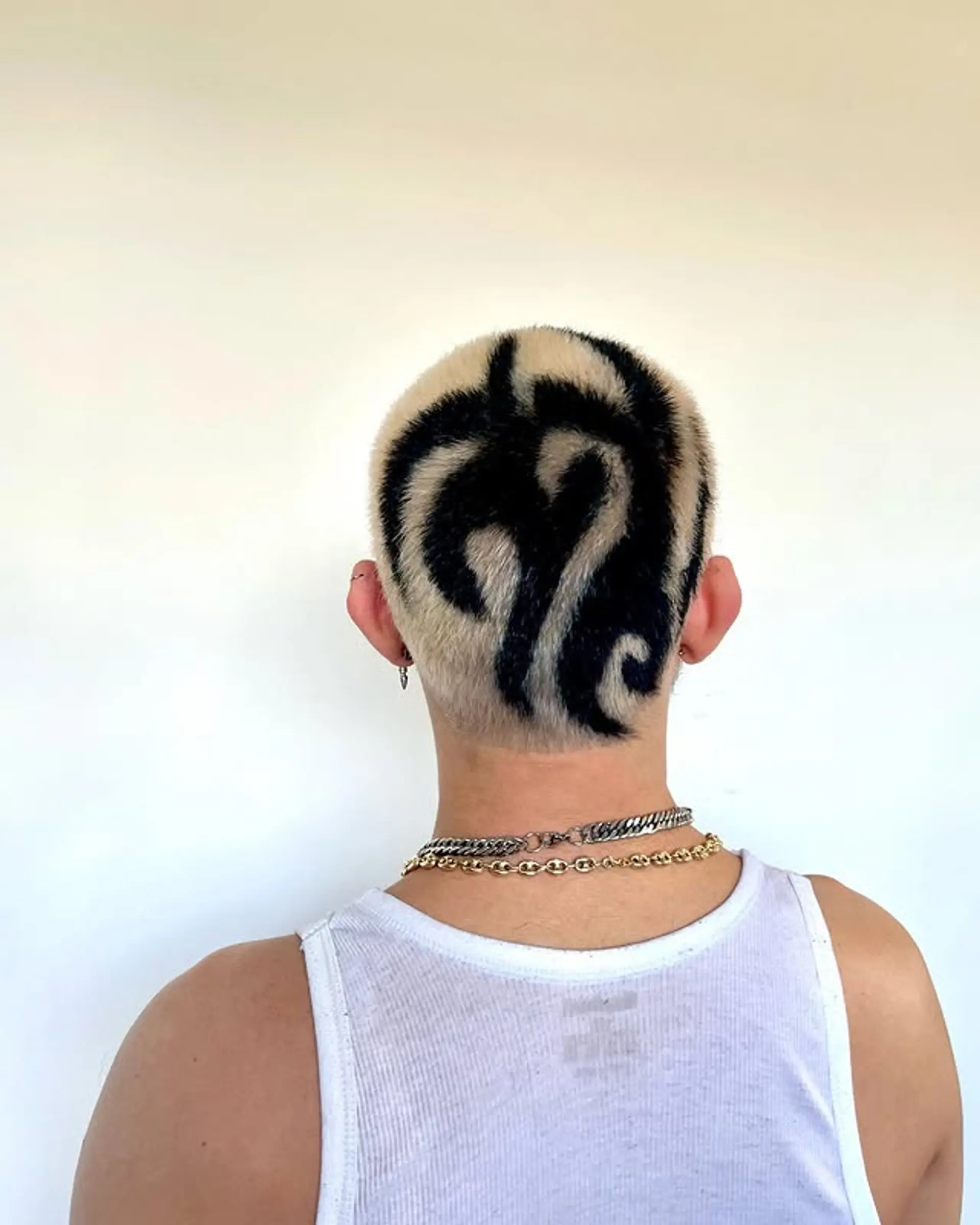 A very short buzz cut featuring a bold geometric design created with contrasting colors. 1