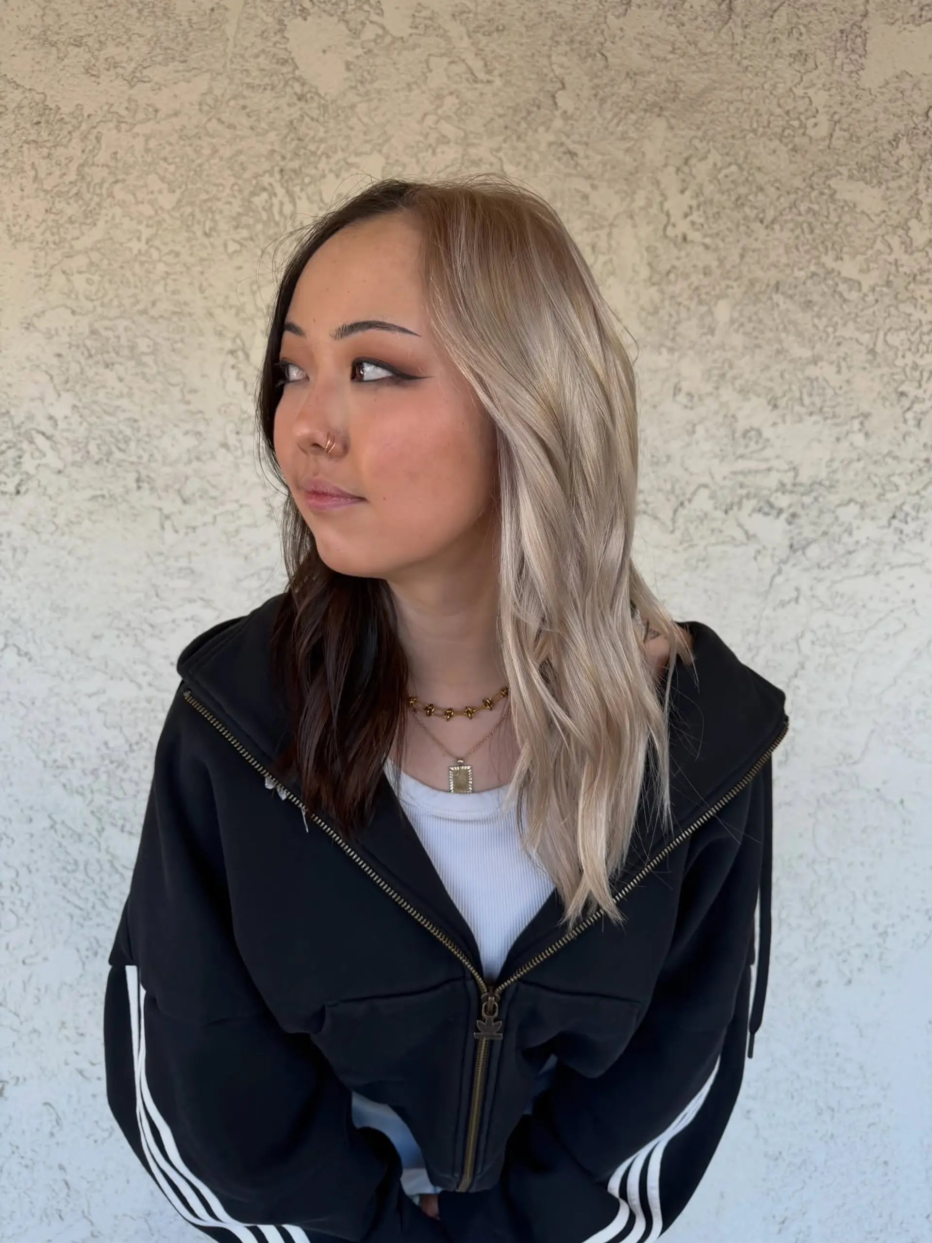 A dramatic split dye style featuring cool platinum blonde on one side and deep dark brown on the other, styled with loose waves. 1