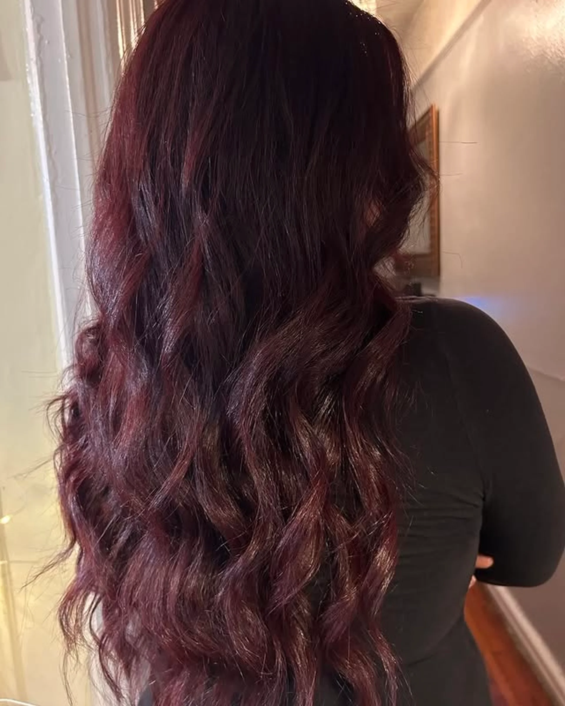 A woman with very long, wavy hair in a rich, deep cherry red color with a glossy, luxurious finish, seen from behind. - Preview 1