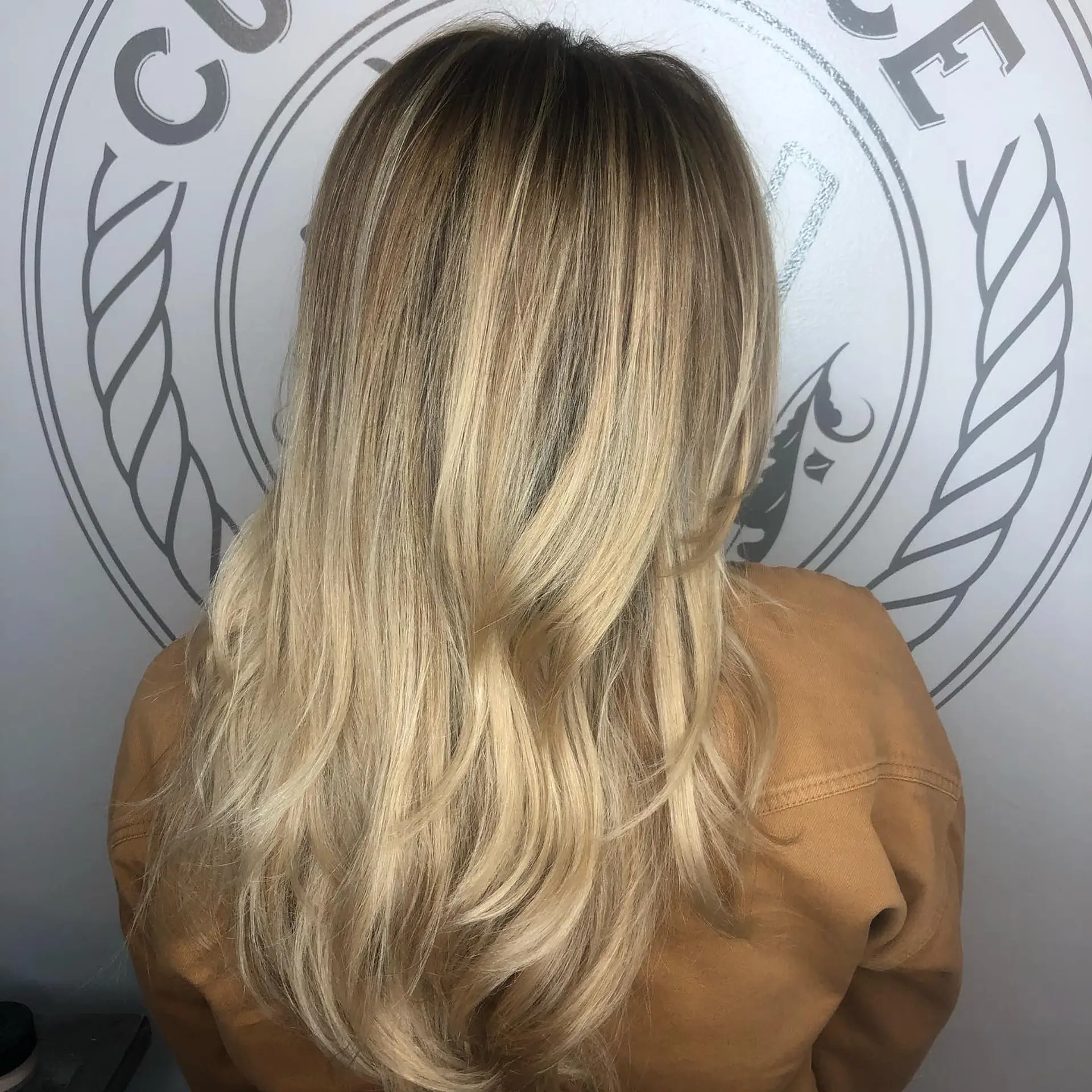 Long warm blonde hair featuring a seamless root melt transitioning into dimensional honey tones with soft, face-framing layers and curved ends. 1