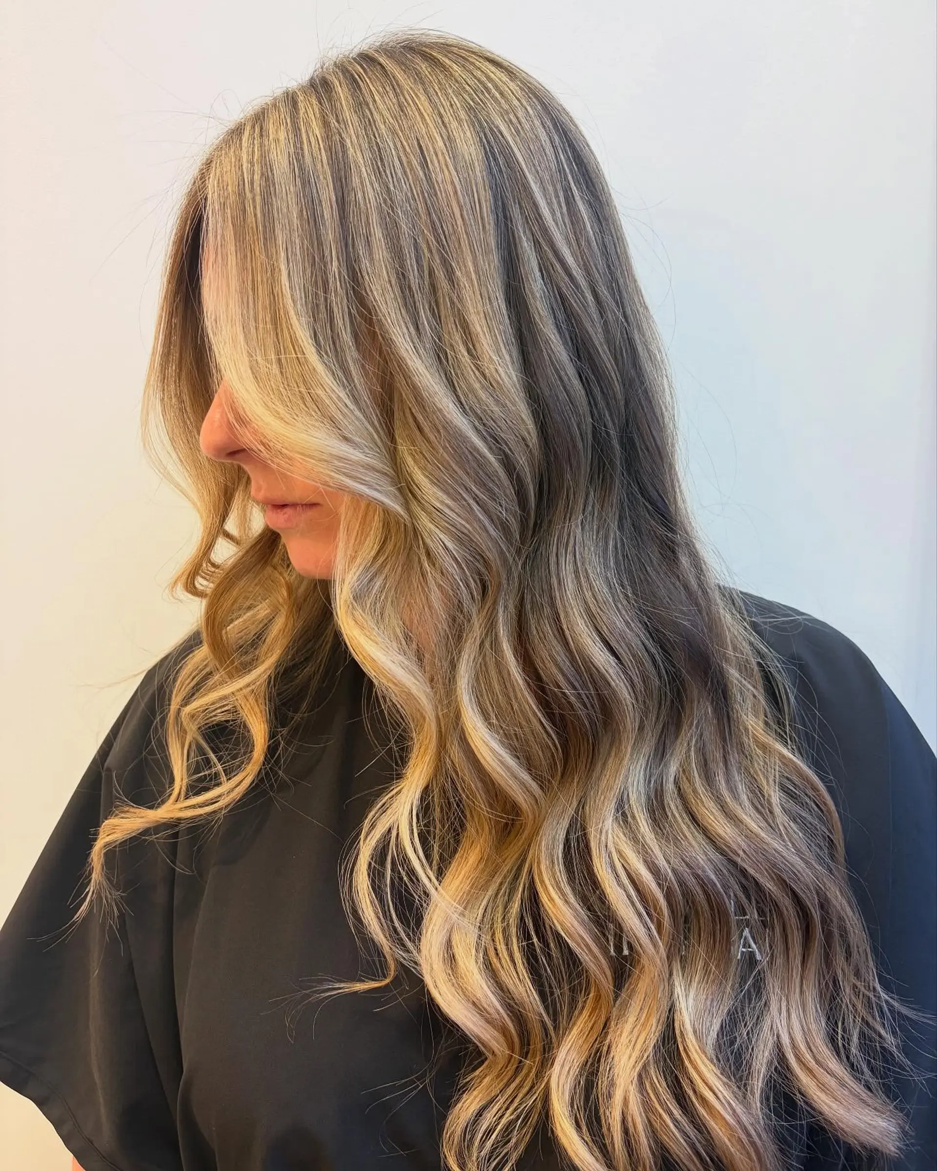 Long lived-in beige blonde hair styled with loose, dimensional waves and face-framing pieces. 1