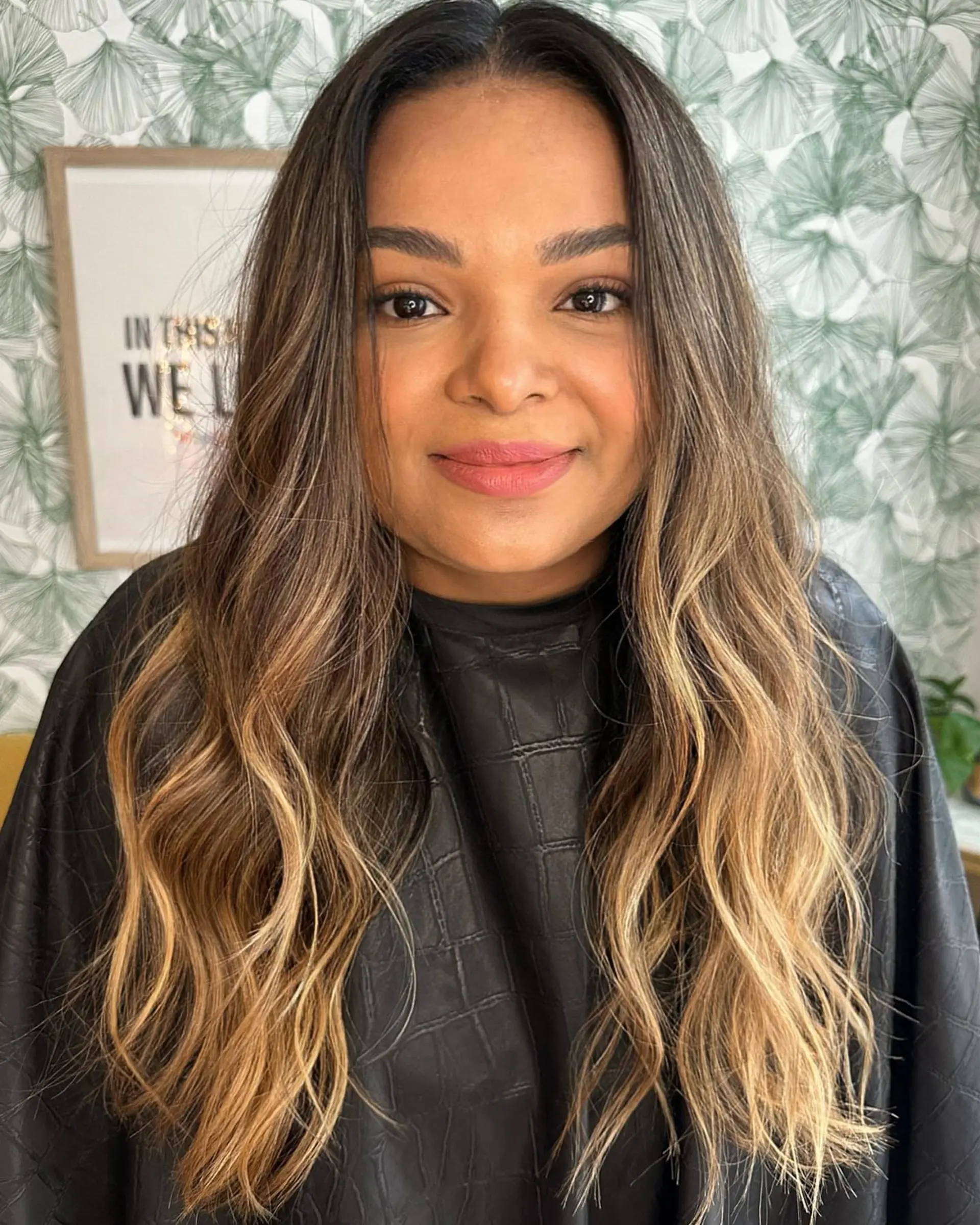 Long dark brown hair enhanced with warm caramel and golden balayage highlights, styled in loose, natural waves. 1