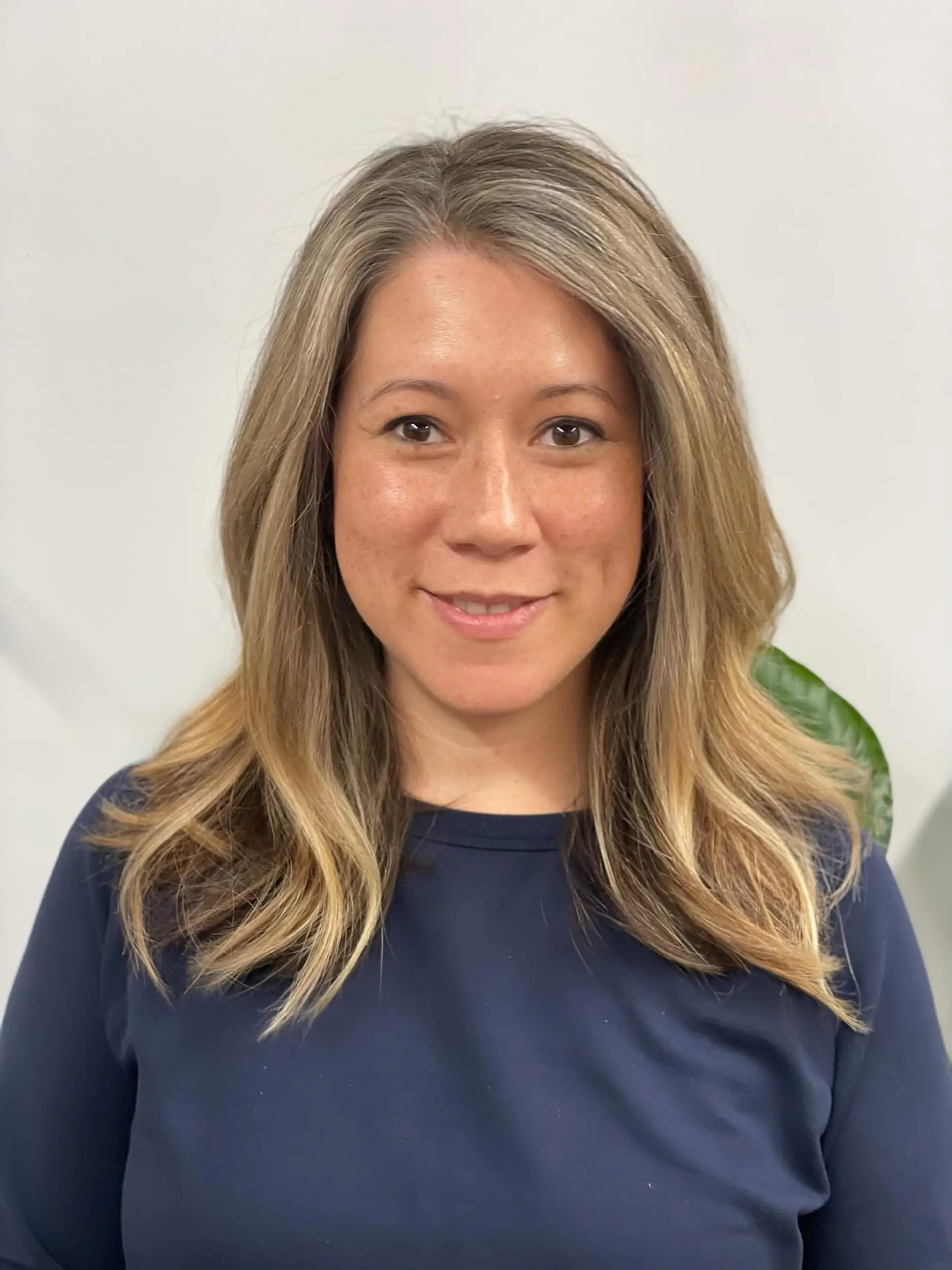 Medium-length layered hair featuring dimensional blonde balayage seamlessly blended with natural gray at the root, styled with soft outward waves at the ends. 1