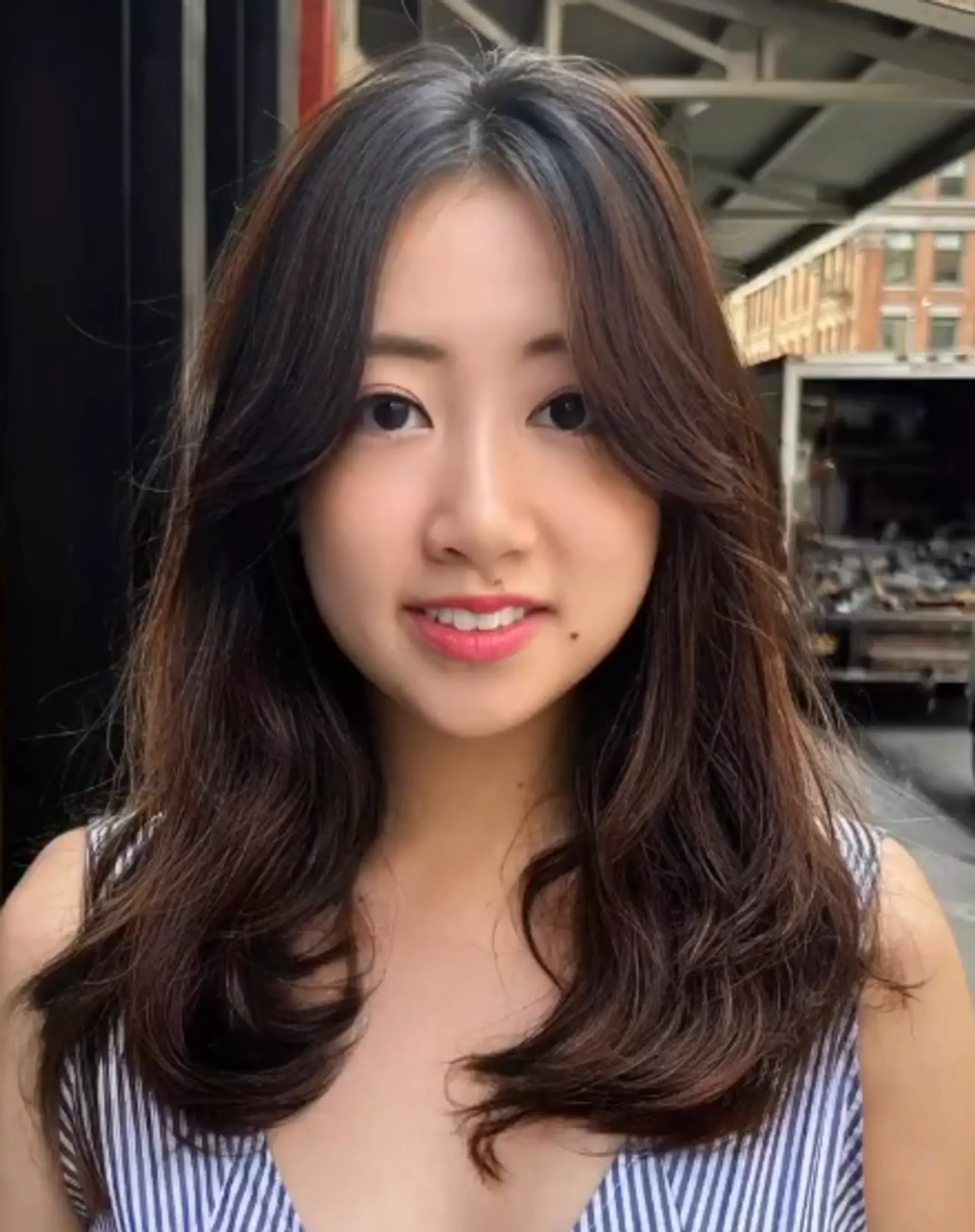 Soft layers with wavy, medium-length dark brown hair. The style is face-framing and features a natural shine with a casual chic look, gently tousled for a relaxed appearance. 1