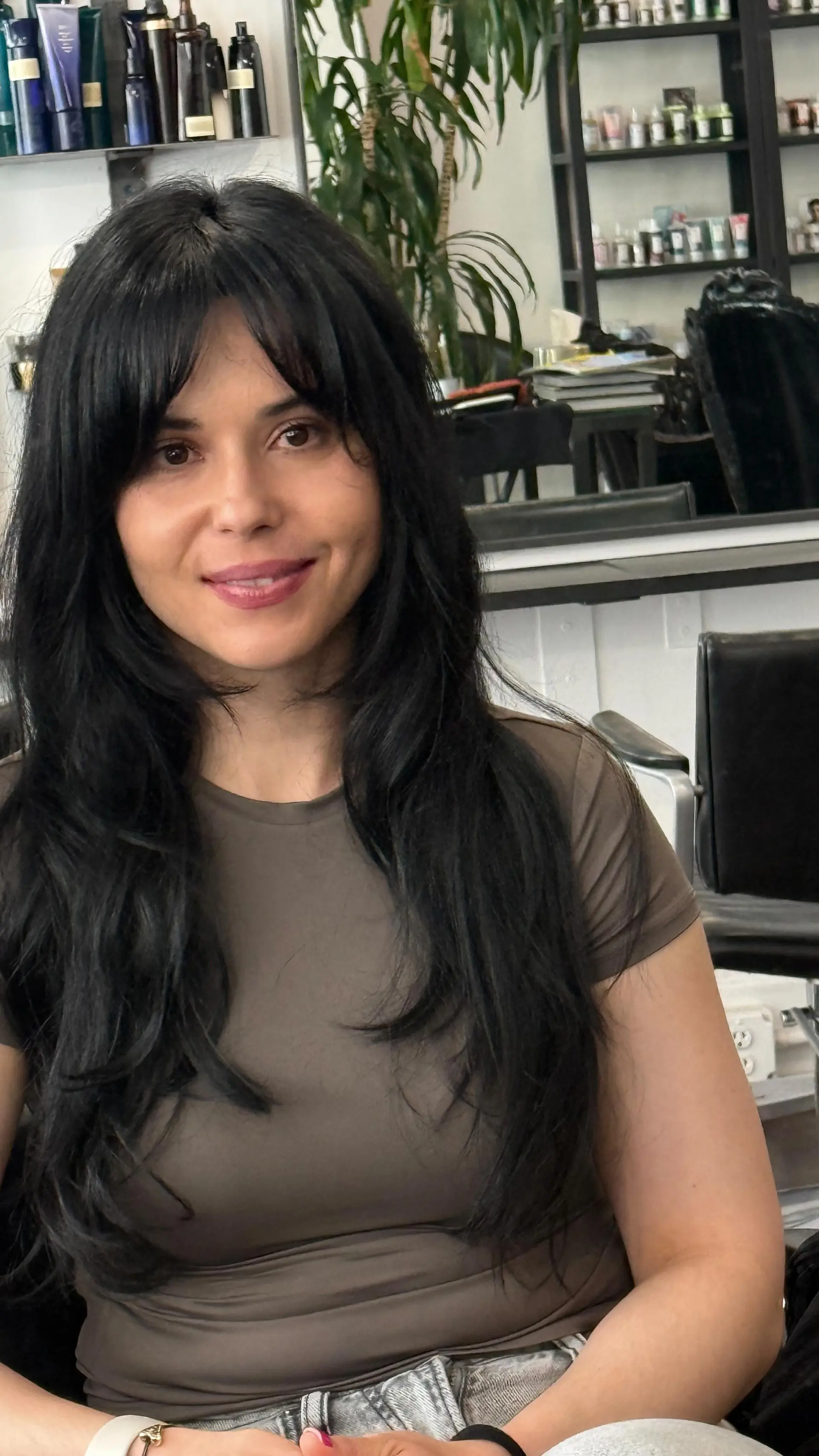 A long black haircut featuring soft face-framing layers, textured ends, and full curtain bangs. 1