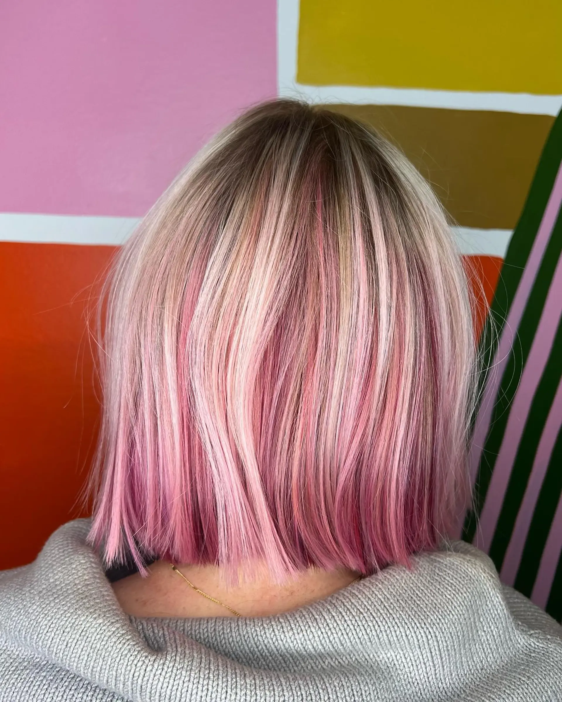 A sleek, blunt-cut bob featuring soft pastel pink highlights woven through platinum blonde and subtle natural roots. 1