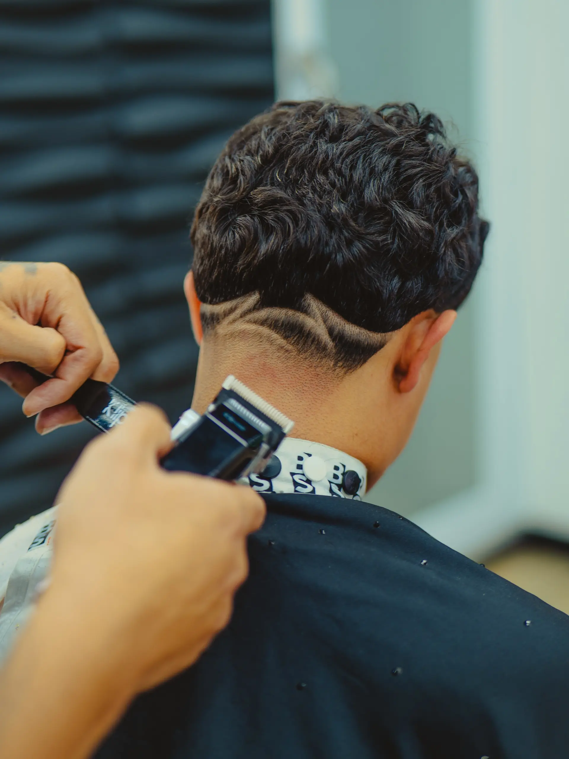 A low neck taper fade accentuated with curved, shaved freestyle line designs across the nape. 1