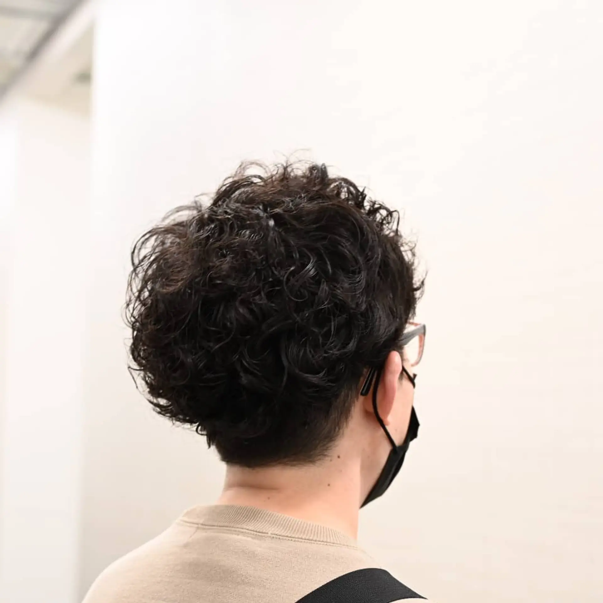 A short haircut styled with voluminous, defined curls on top and a clean, tapered neckline. 1