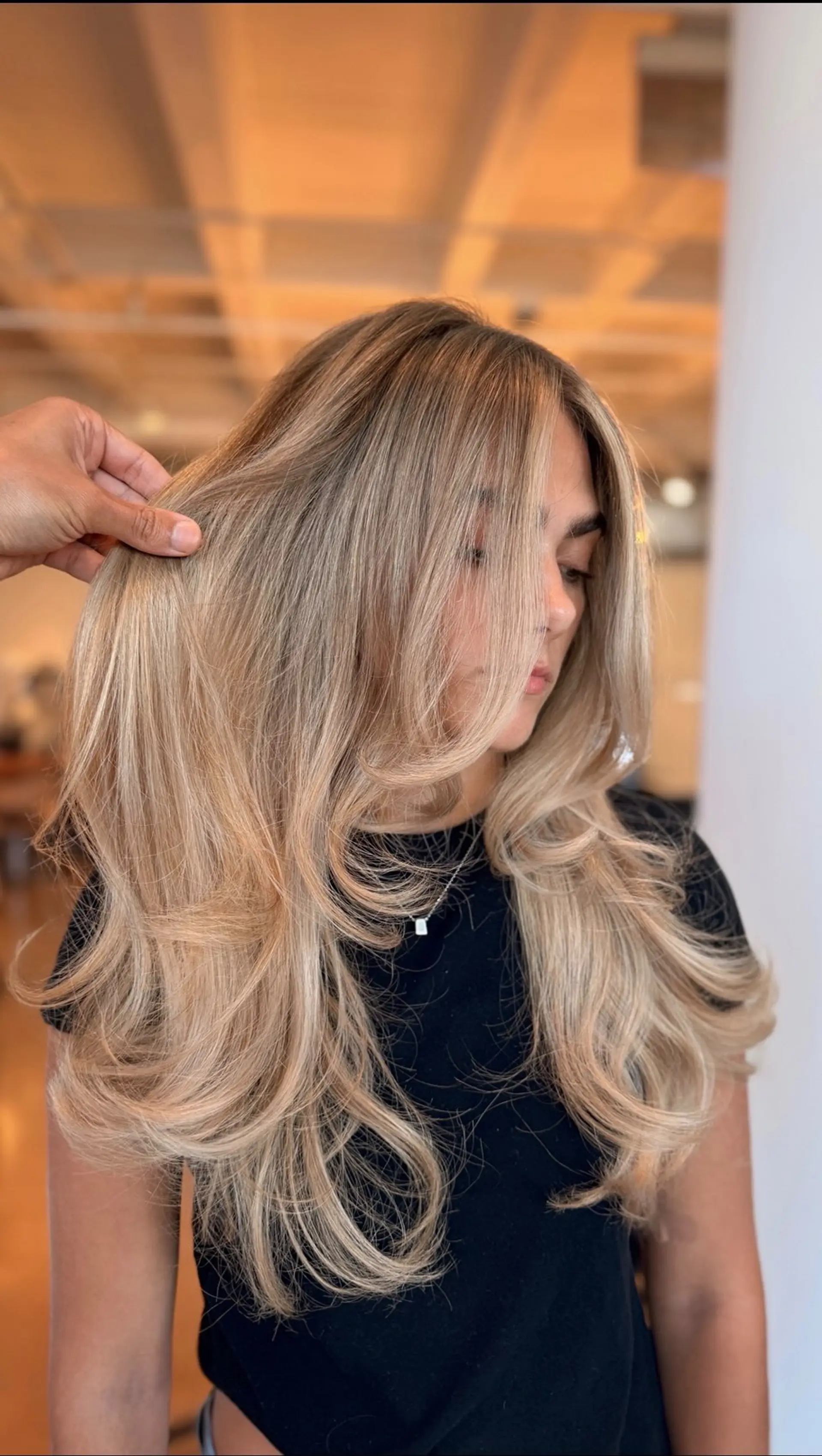 Long creamy blonde hair styled with cascading layers and a voluminous, curved blowout. 1