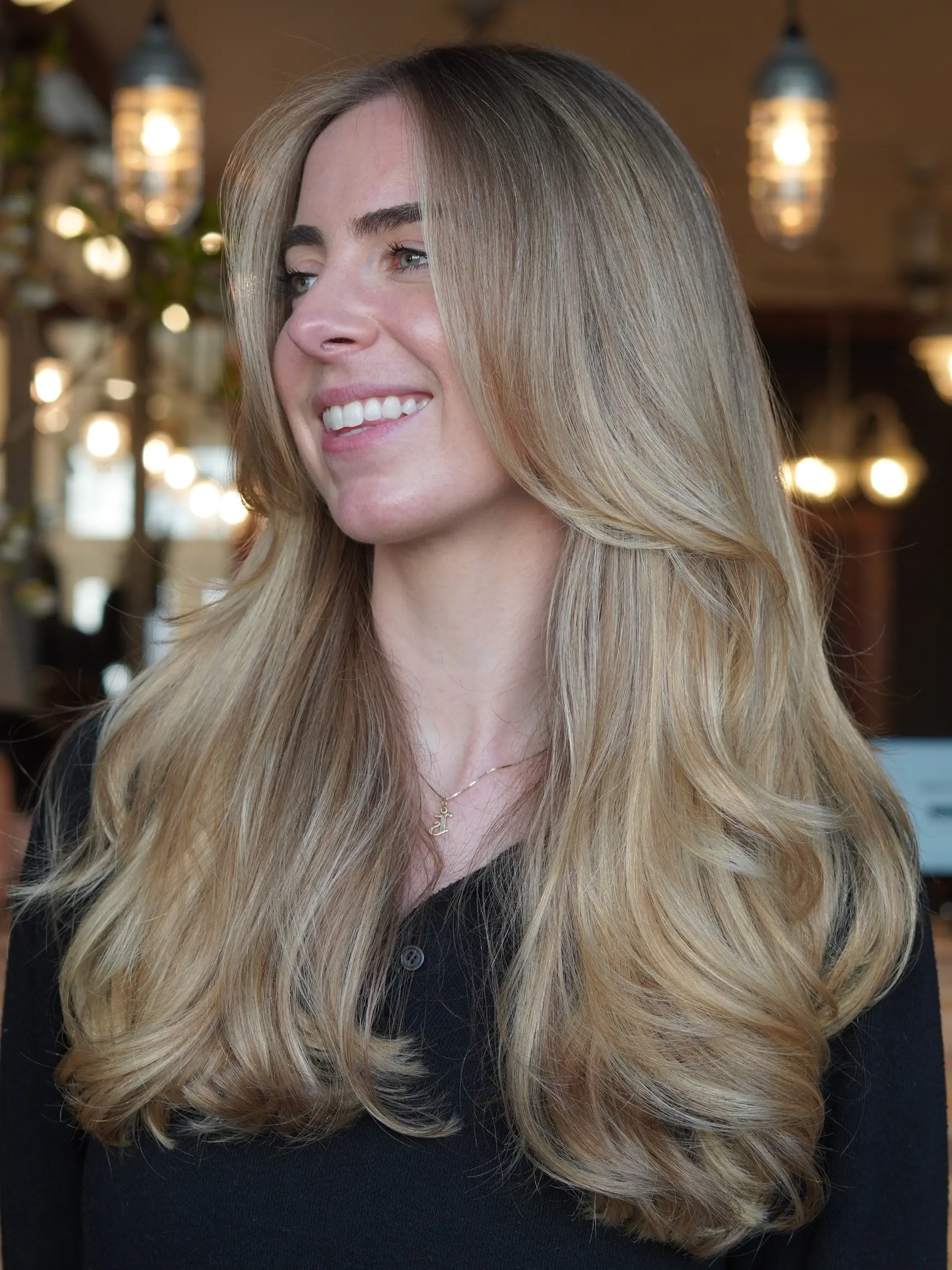 Long beige blonde hair featuring seamless full highlights styled into a voluminous blowout with soft face-framing layers. 1
