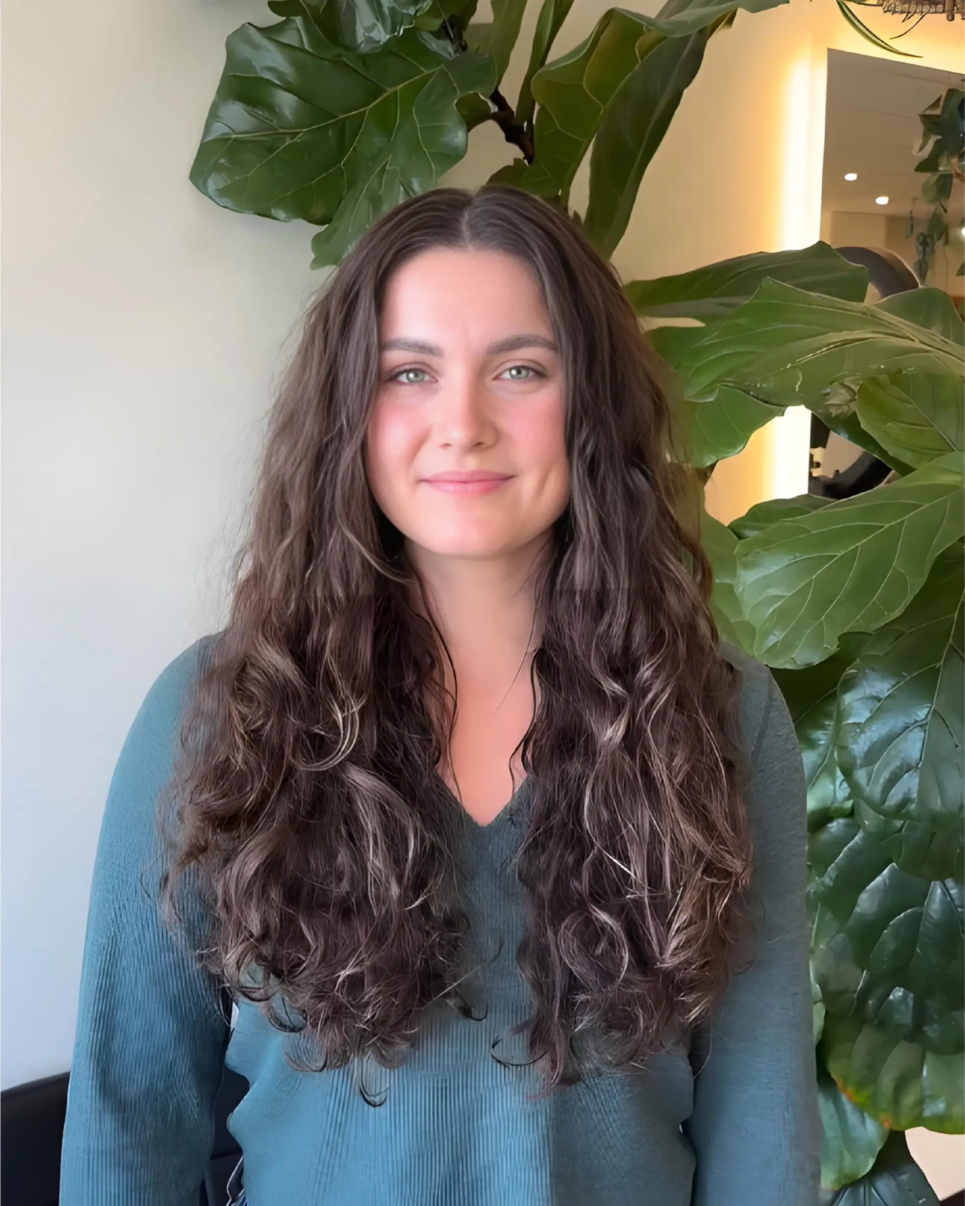 Long, naturally wavy and curly brunette hair styled with soft layers for enhanced volume and definition. 1