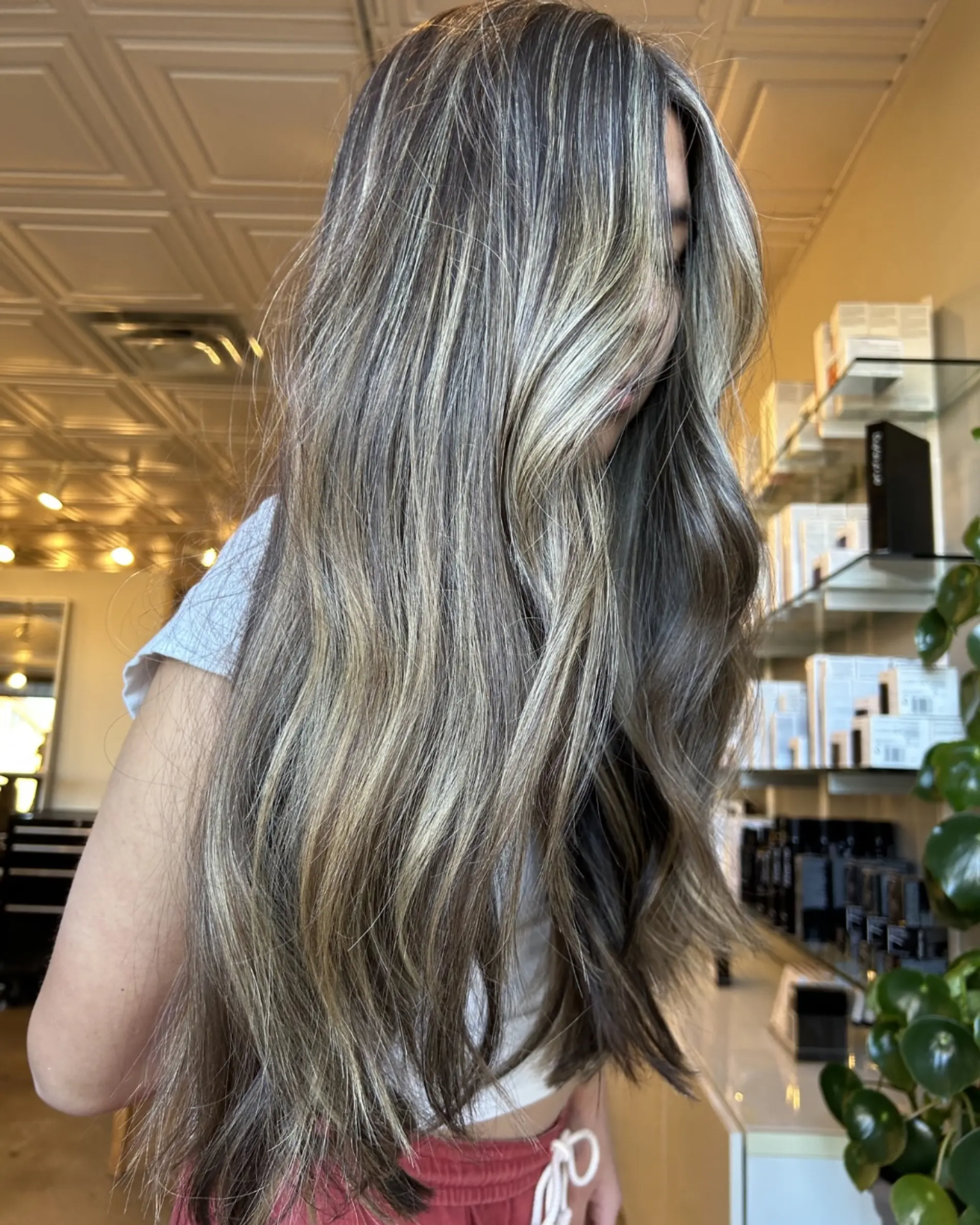 Long dimensional bronde hair styled with subtle waves, blending deep brunette lowlights with cool blonde highlights. 1