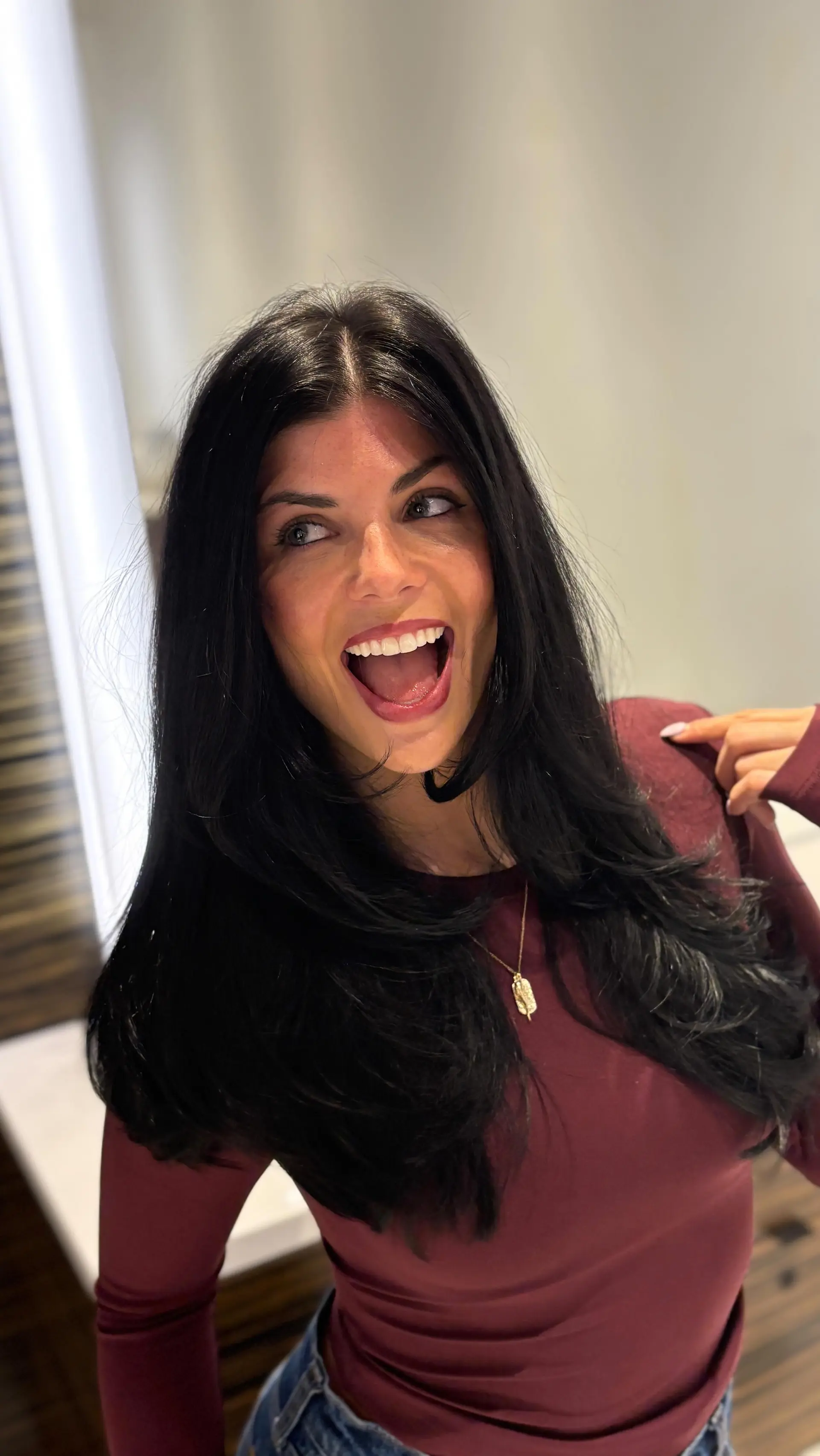Long jet black hair styled into a smooth, bouncy blowout with face-framing layers and soft curved ends. 1